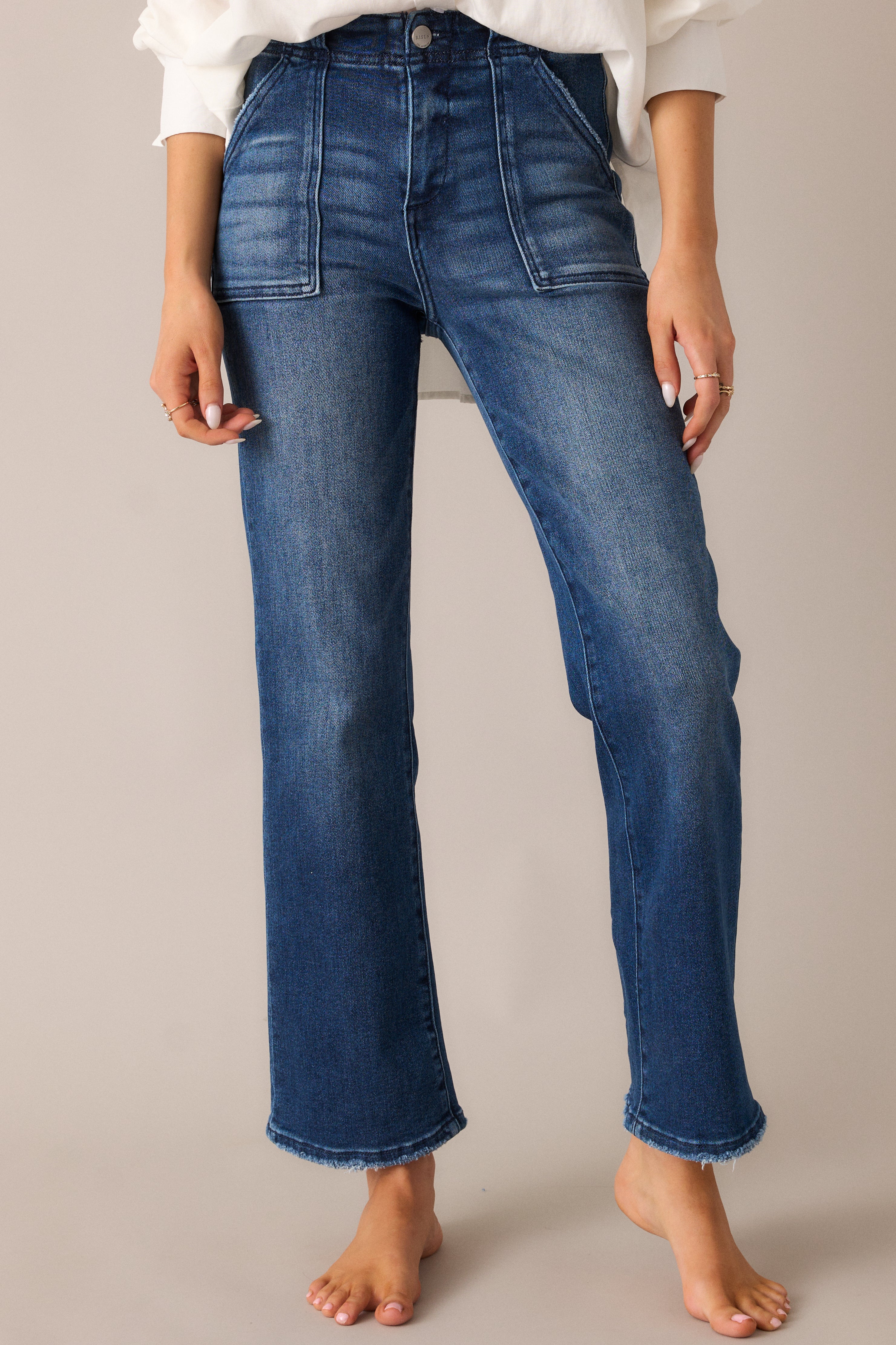 Detailed shot of the large front pockets and the button and zipper closure, showing off the tailored fit of these dark wash jeans with a high waist design.