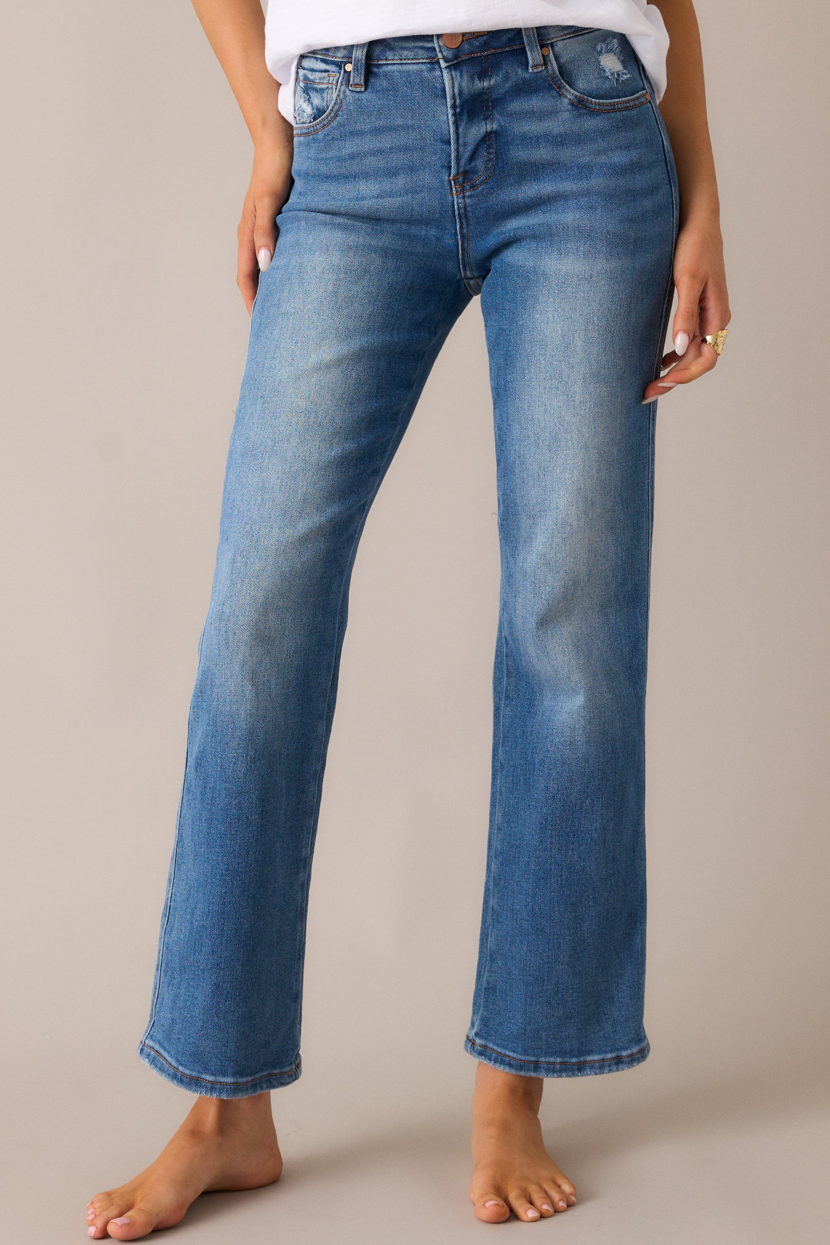 Straight-leg medium wash jeans highlighting the fabric texture, subtle distressing, and front pocket detail.