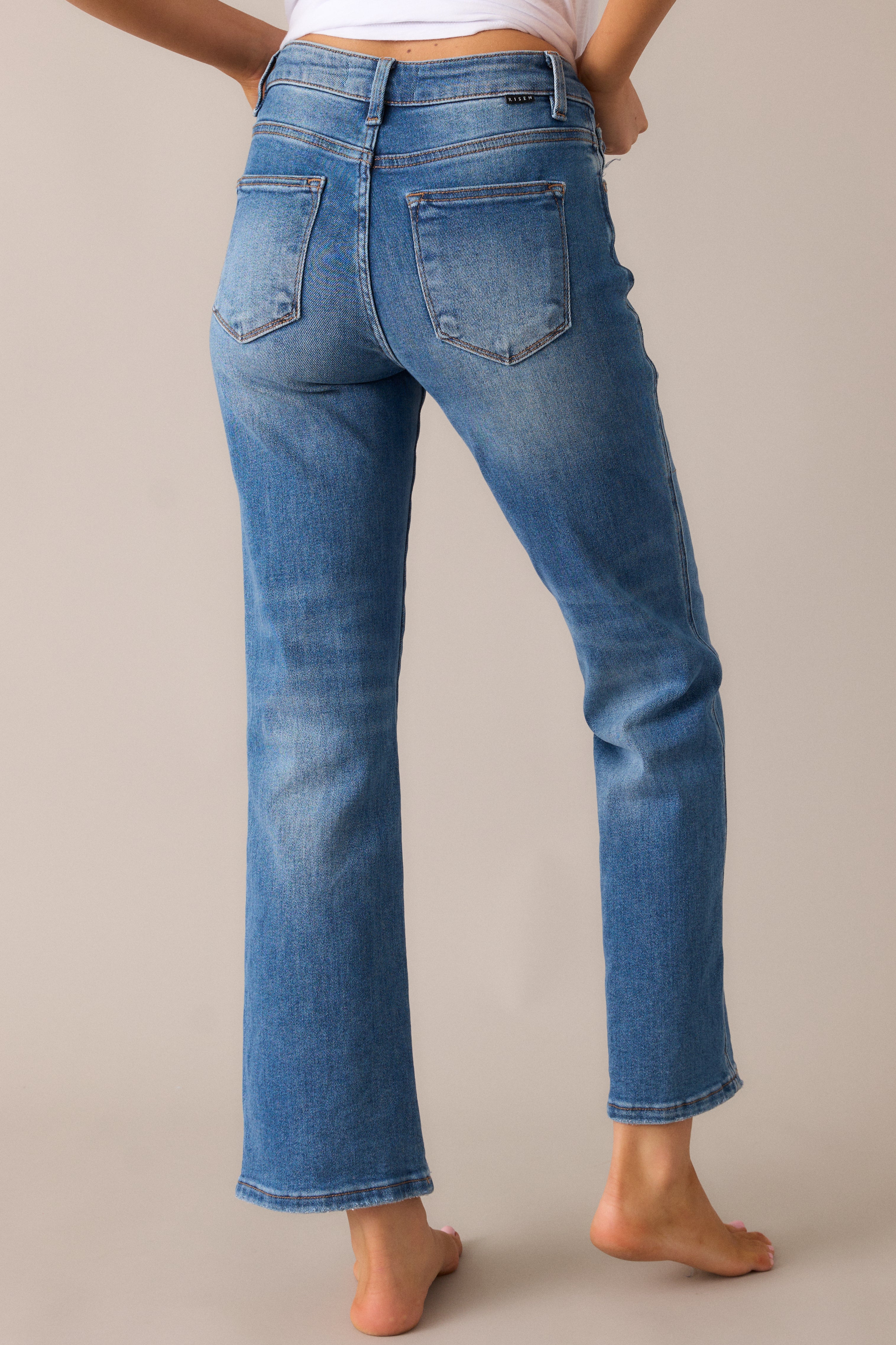 Medium wash jeans displaying the high-rise design, back pockets, and straight-leg cut from the back angle