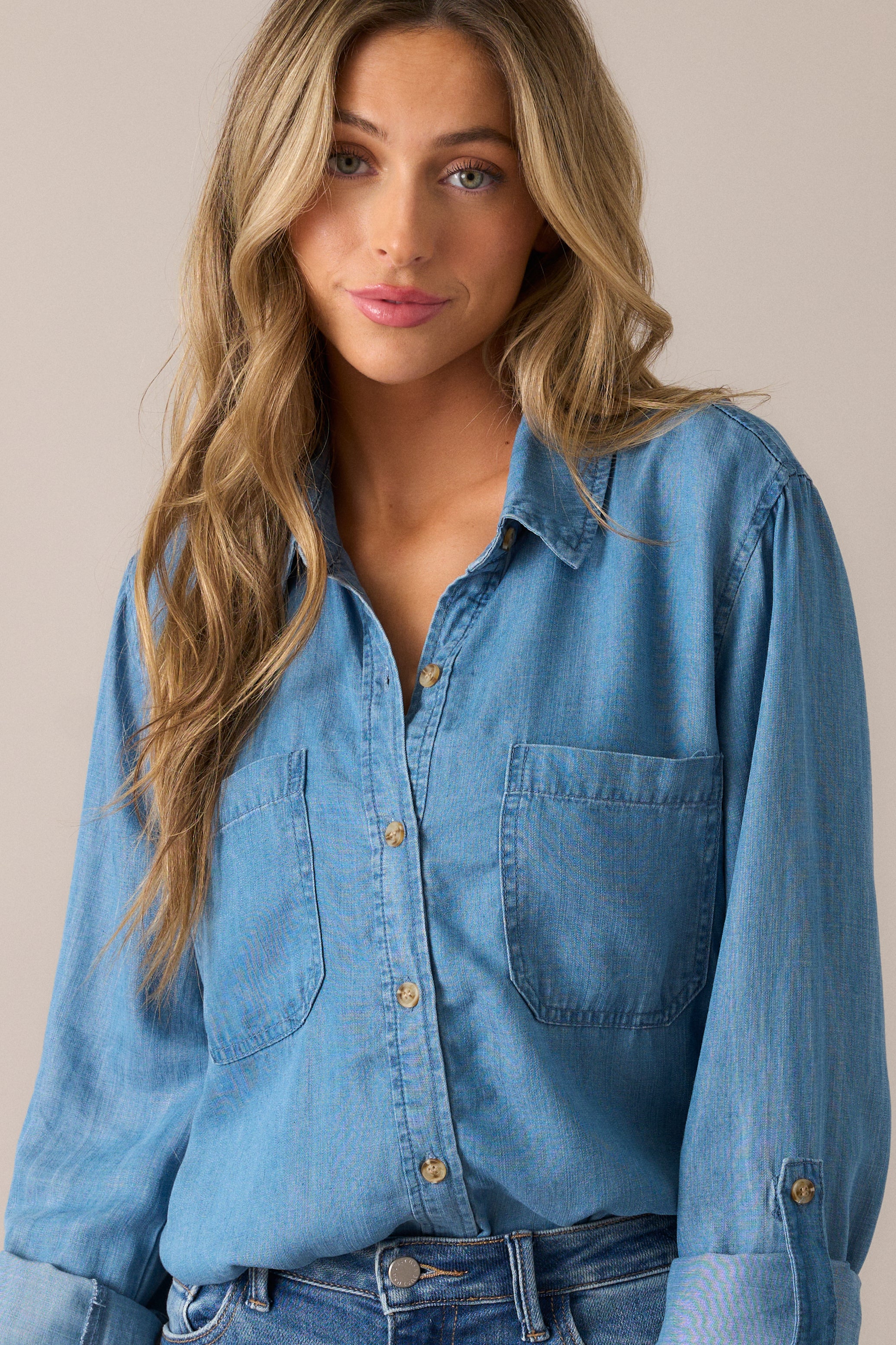 Effortlessly chic chambray blouse with 3/4 sleeves, button cuffs, and two functional front pockets, creating a relaxed yet polished silhouette.