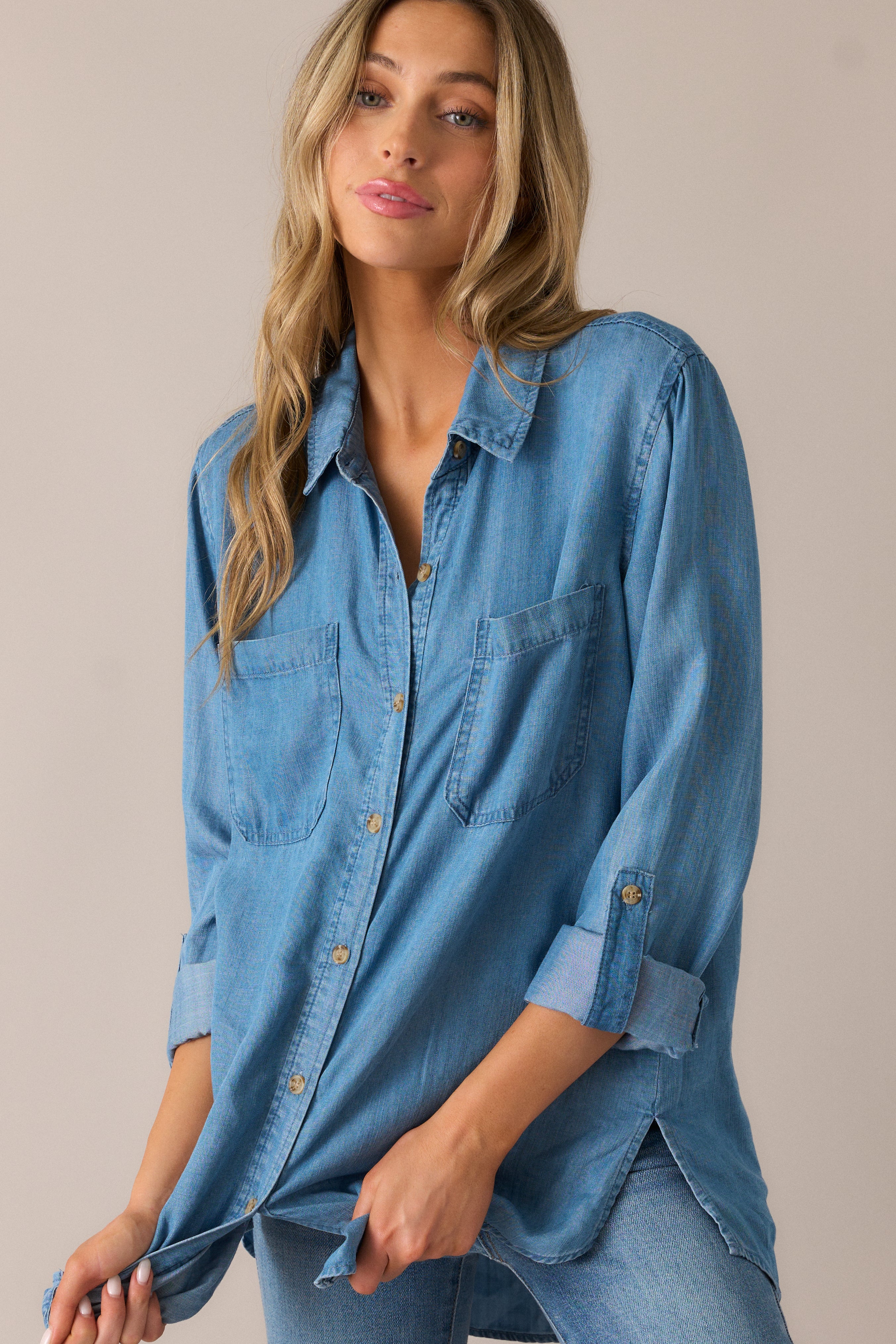 Light and breezy chambray blouse featuring a button-front design, curved split hem, and buttoned cuffs on the 3/4 sleeves for a fresh, casual feel.