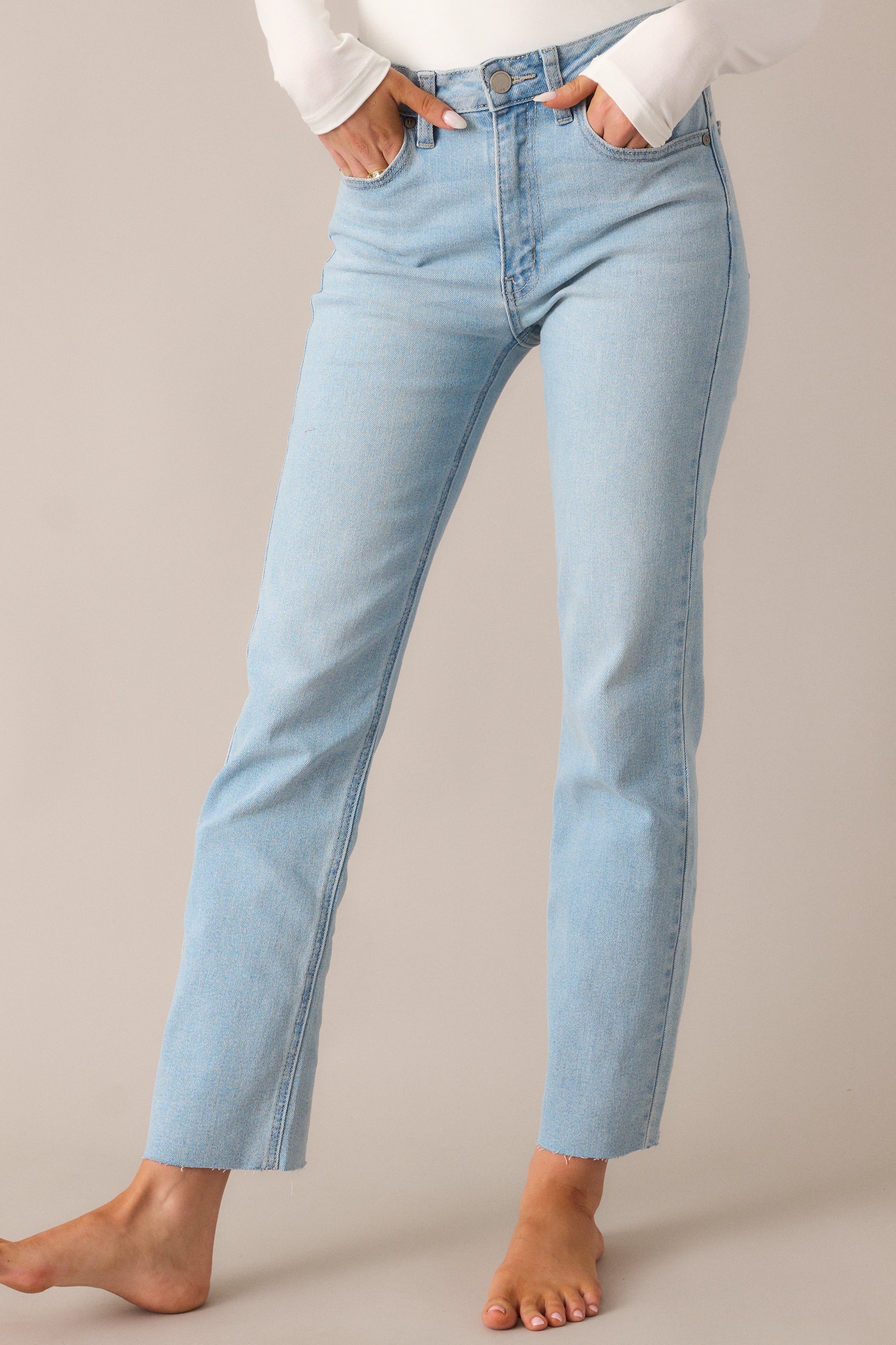 Close-up shot of the mid-rise waist and straight leg fit, highlighting the functional belt loops, pockets, and the classic button and zipper closure on these light wash jeans.