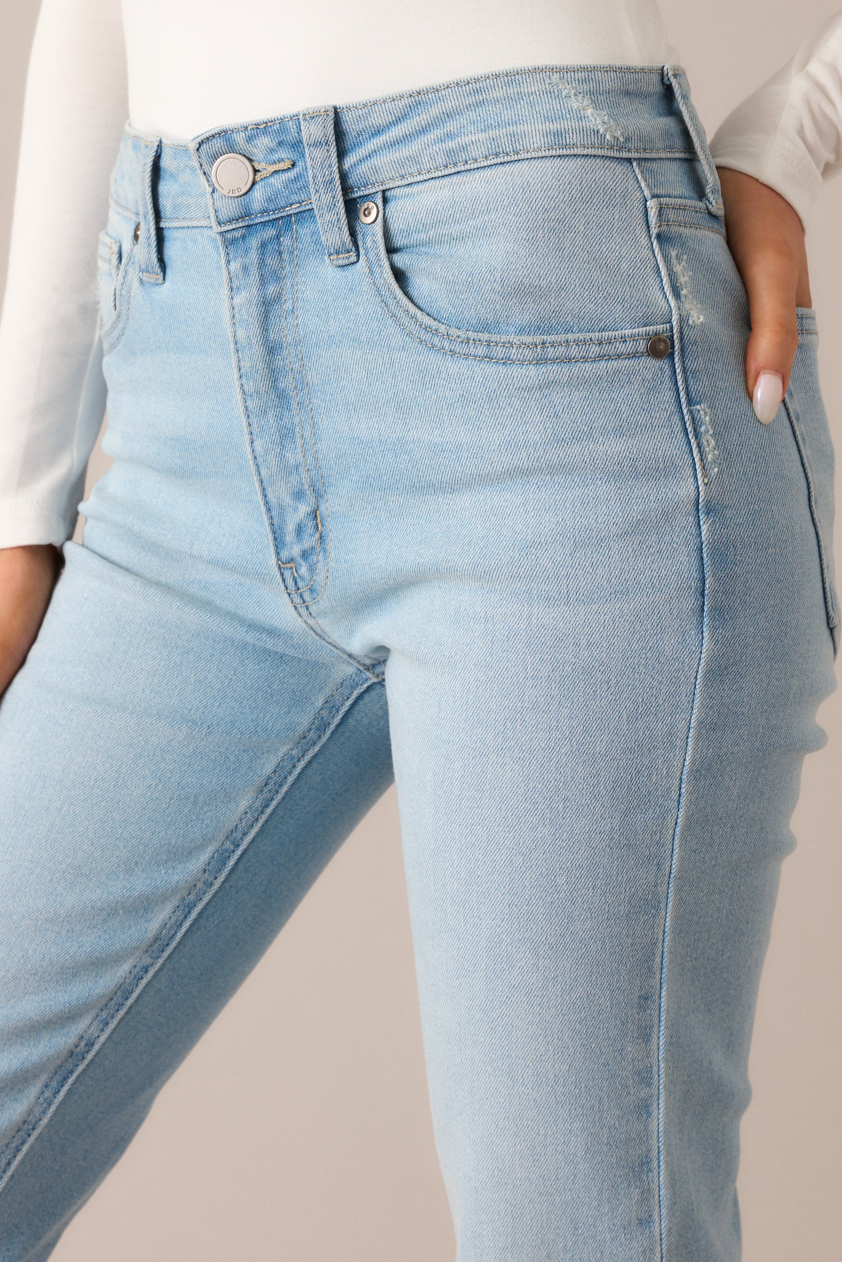  A focused look at the button and zipper closure, emphasizing the smooth light wash fabric and the straight leg fit, with functional pockets for a practical touch.