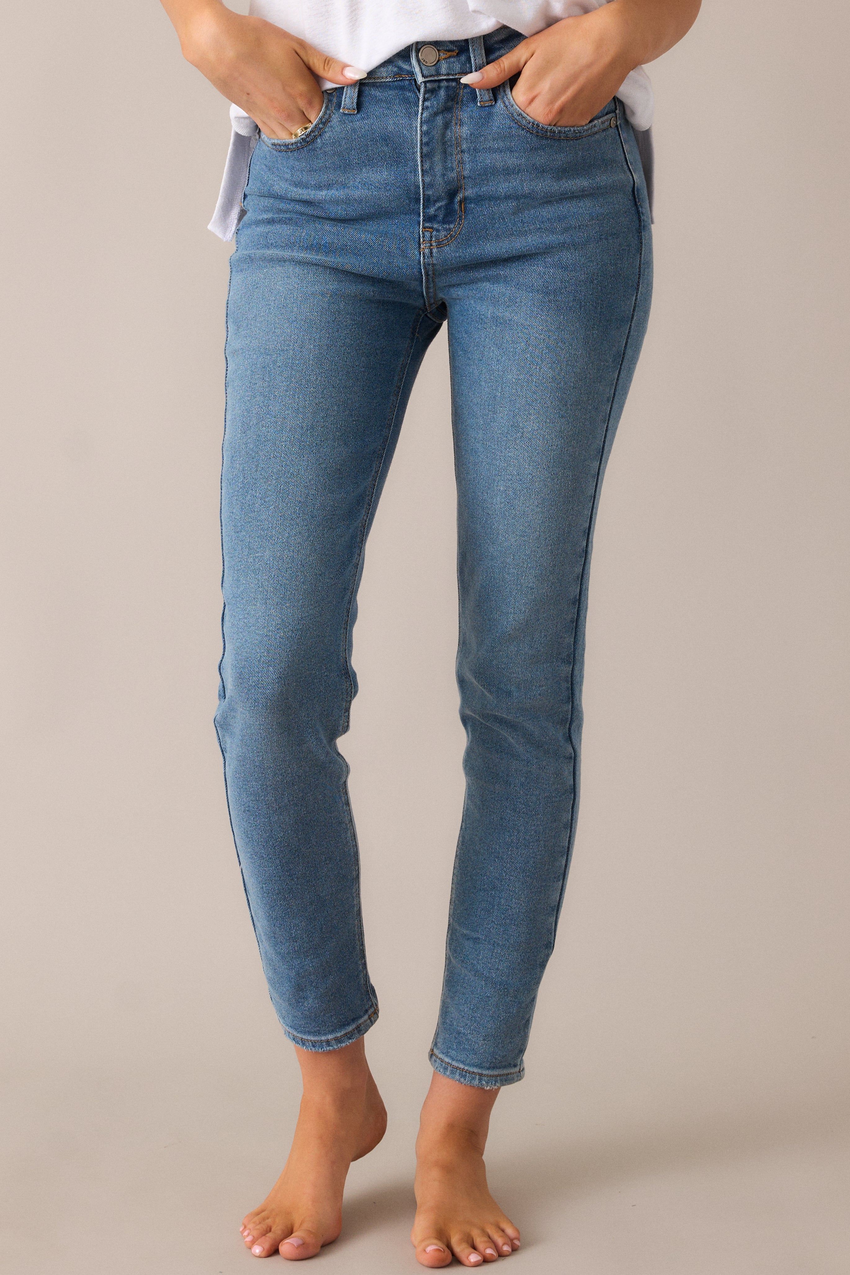 Close-up of the medium-wash jeans, showcasing the slim fit, functional pockets, and the chic mid-rise waistline