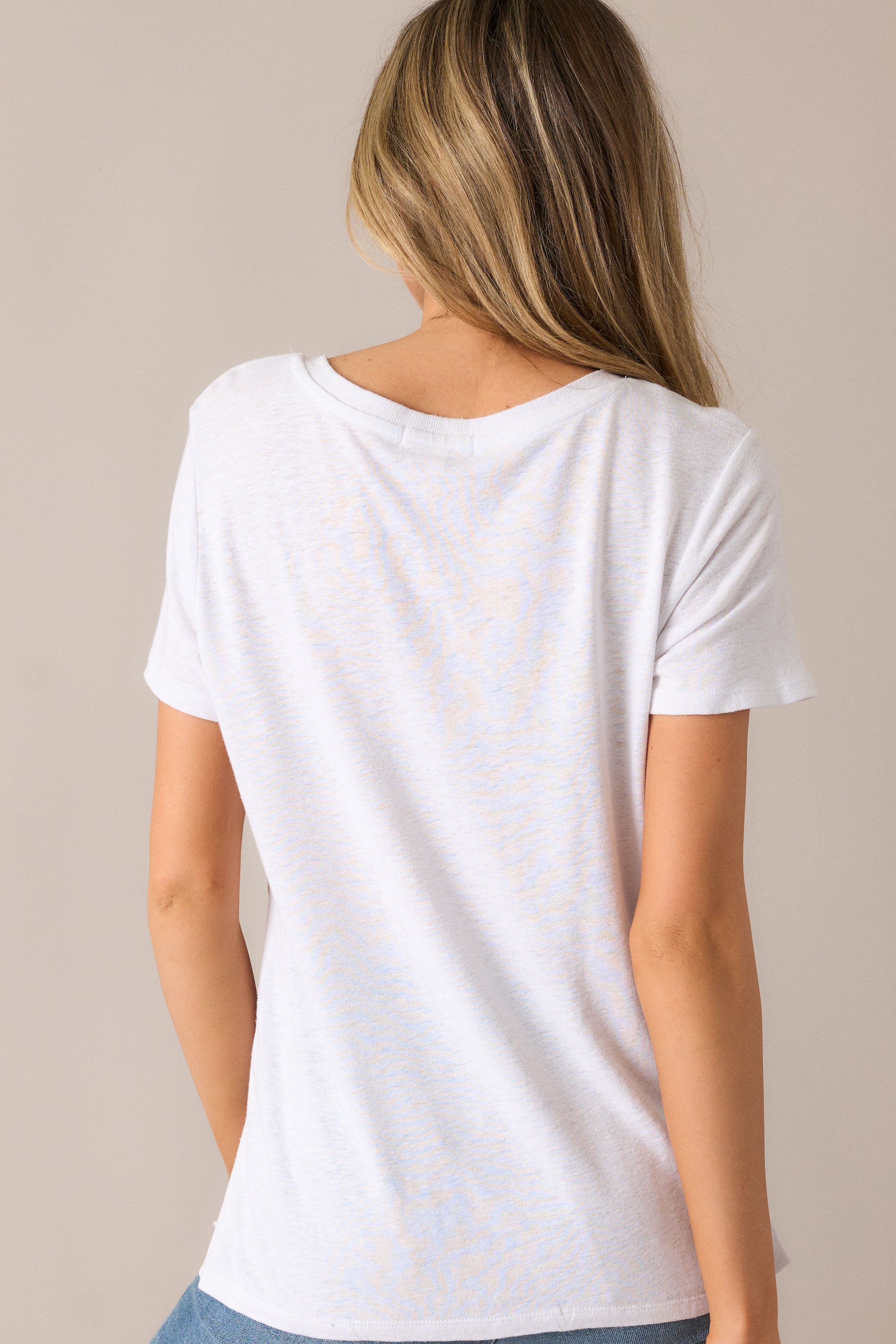 The white tee from the back, showcasing the loose, comfortable fit and the stylish split hemline that adds a contemporary touch to the design.