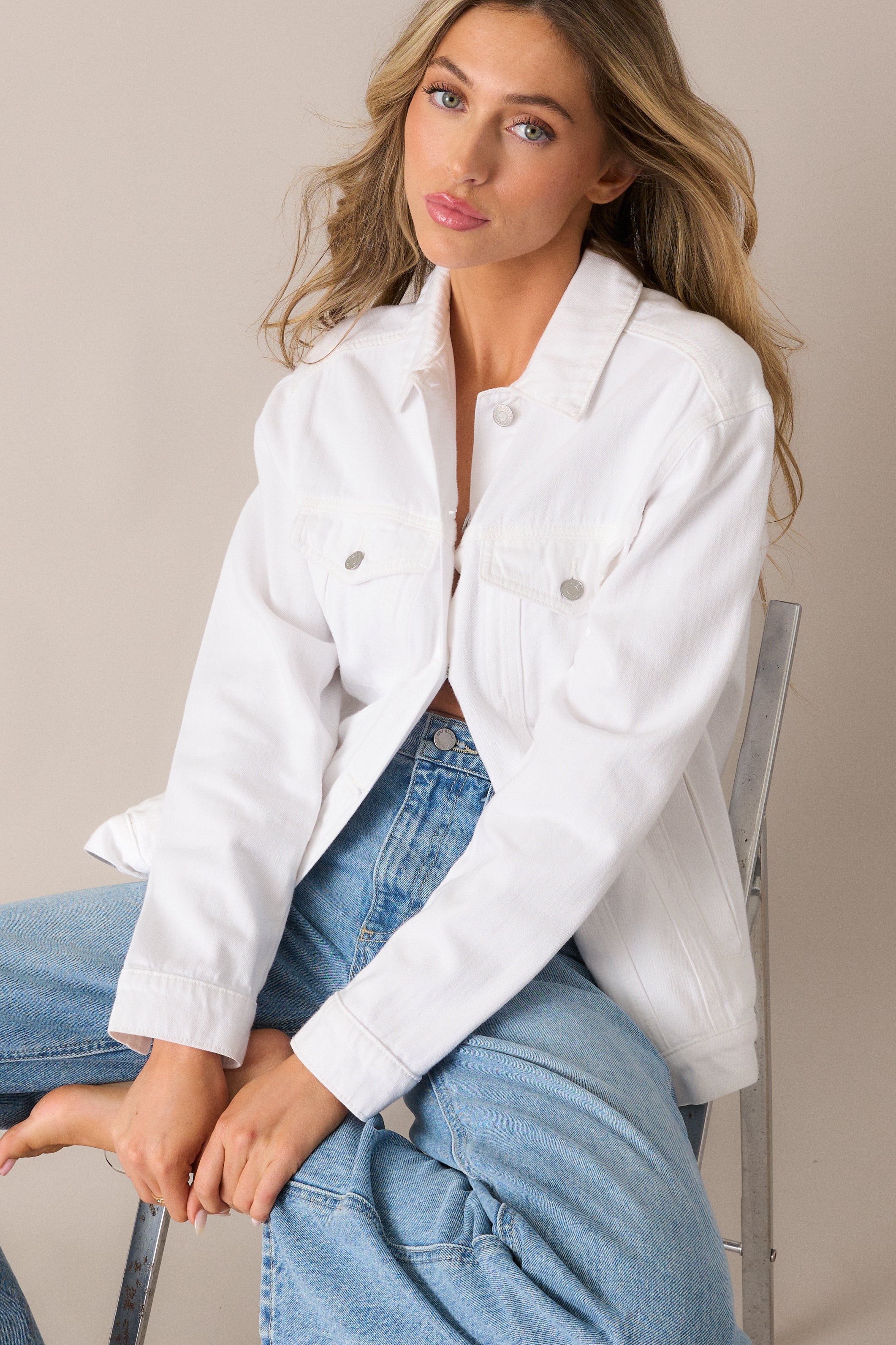 Chic white denim jacket featuring a button front, chest pockets, and buttoned sleeves, creating a clean, structured silhouette.