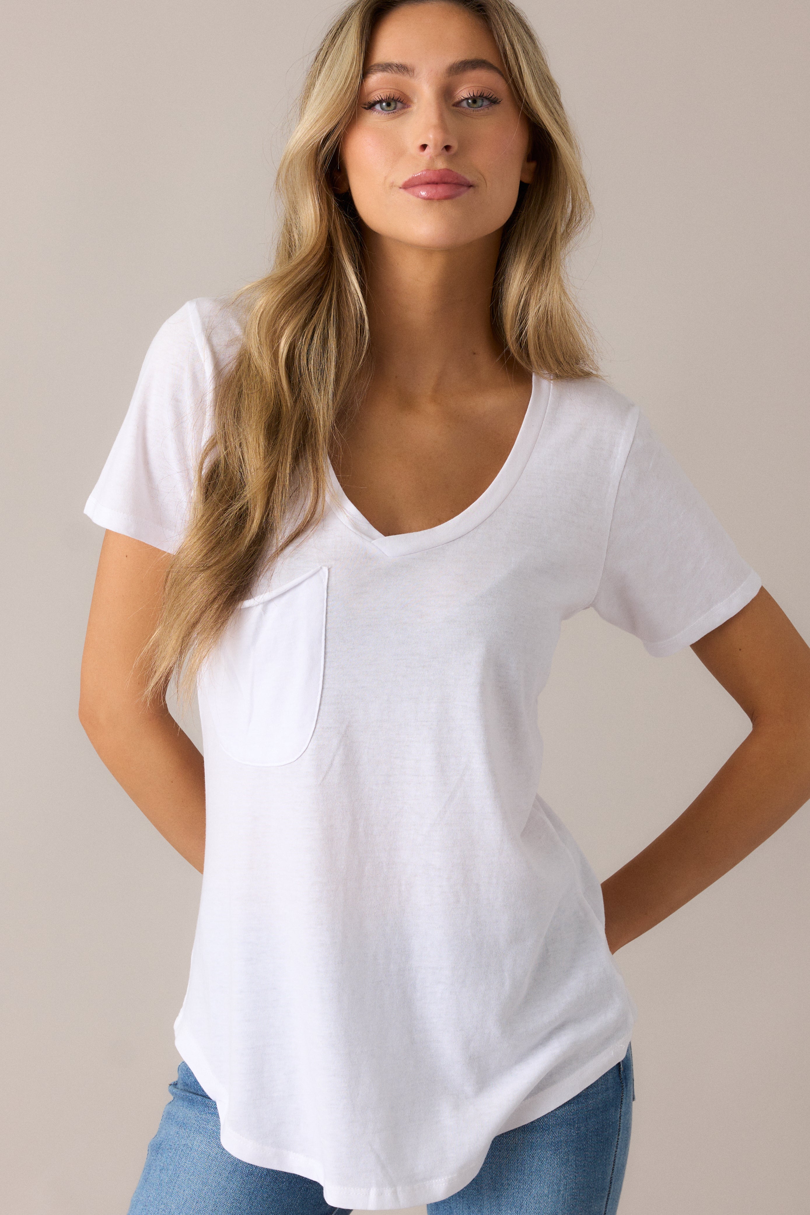 Relaxed burnout jersey tee featuring a curved v-neckline, raw edge breast pocket, short sleeves, and a stylish scoop hem, perfect for a casual-chic look.