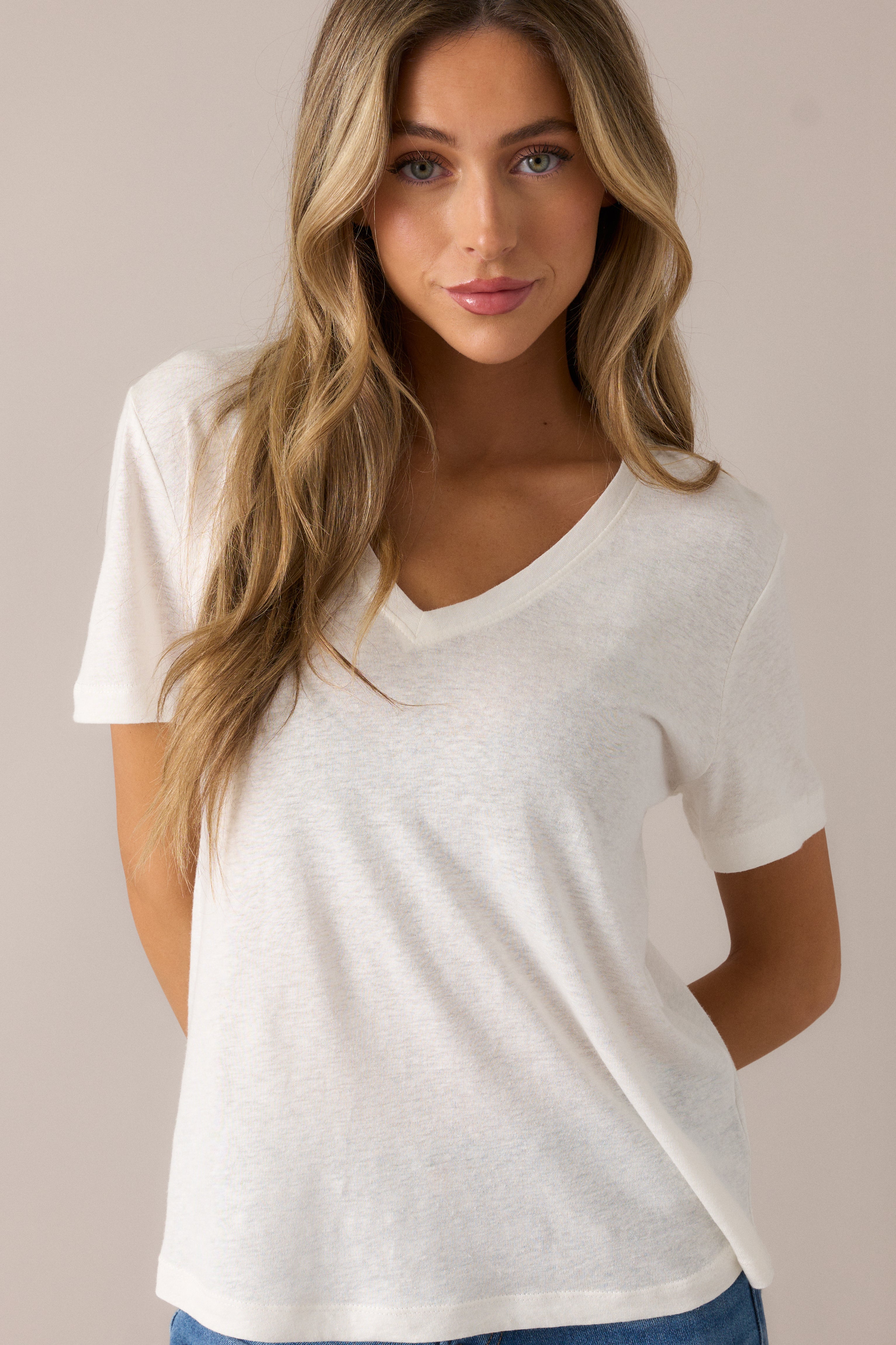 Highlighting the relaxed fit and subtle curves of the scoop hemline on the ivory tee.