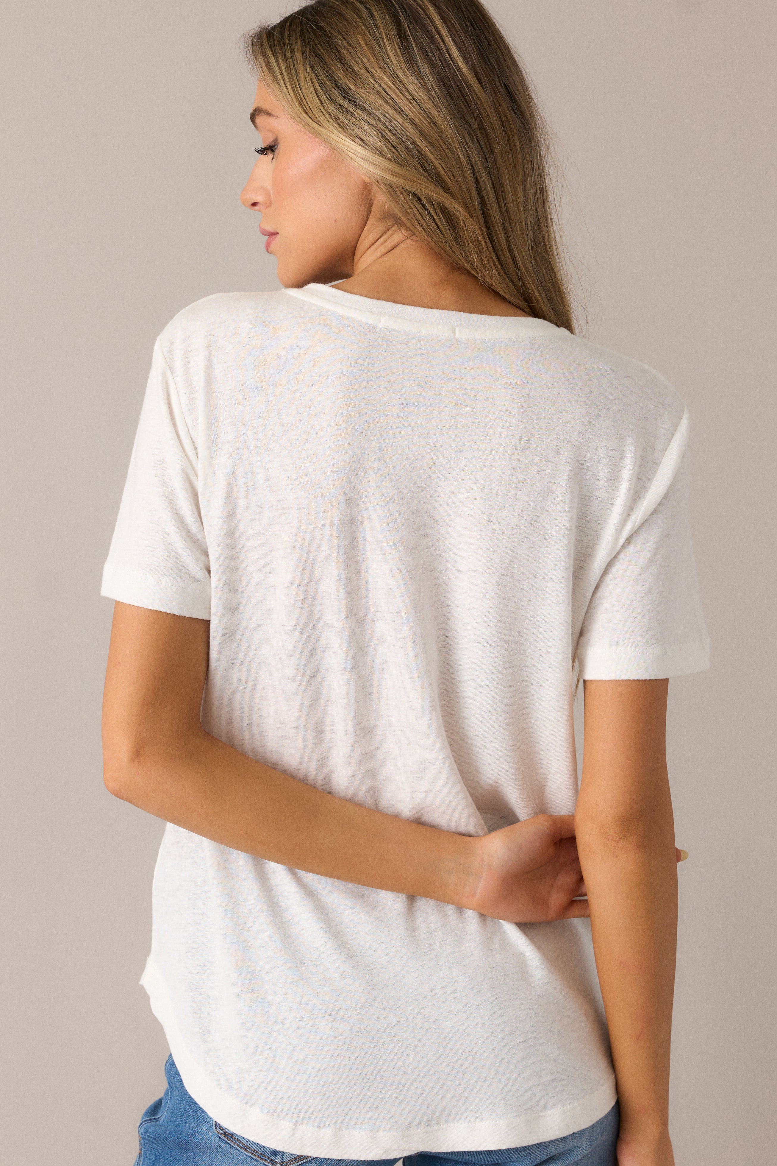 The ivory tee from the back, showcasing the smooth washed fabric and relaxed fit of the short sleeves and scoop hemline.