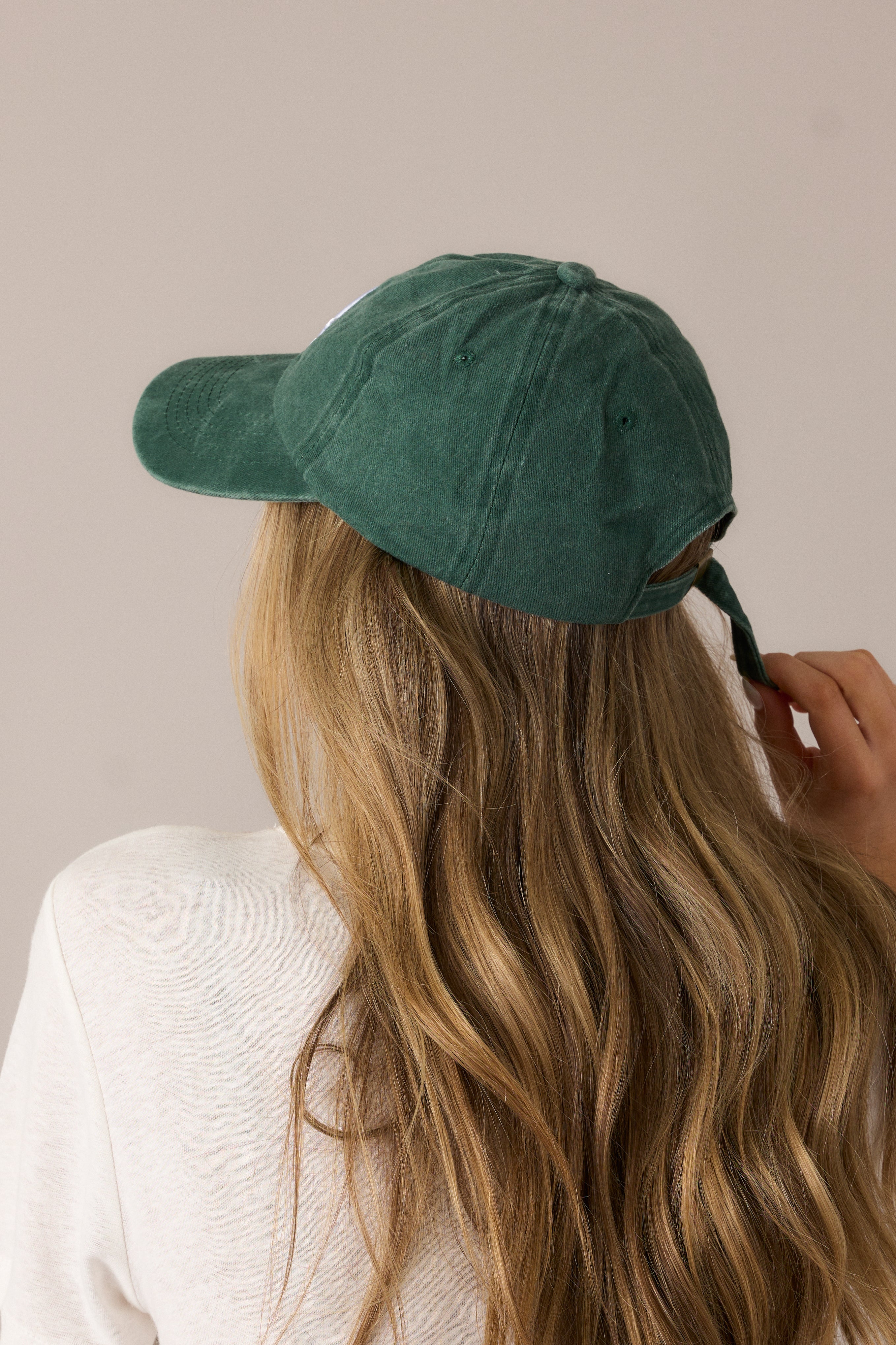 The emerald baseball cap from the back, featuring the adjustable buckle and smooth fabric finish.