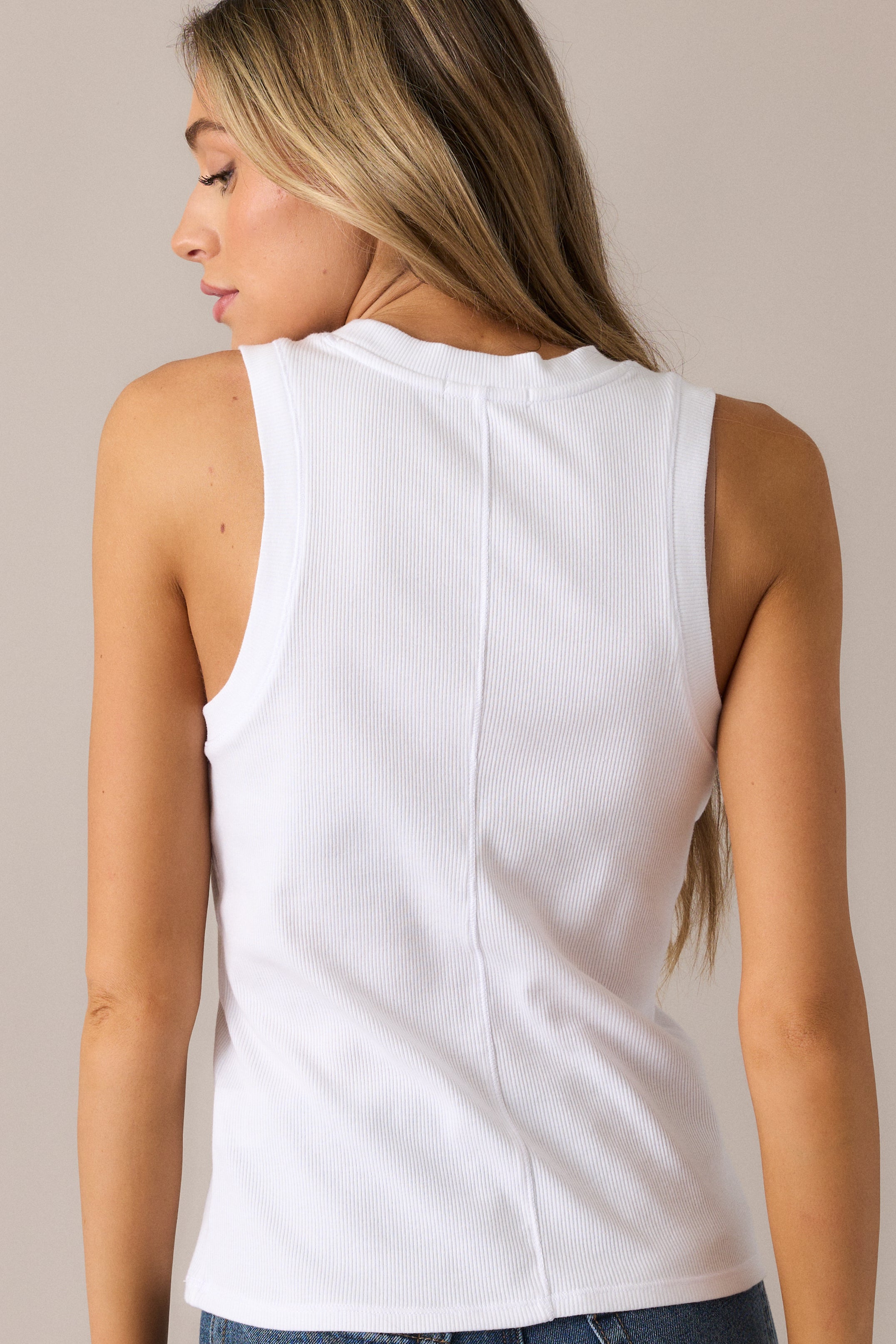 The white tank from the back, showcasing its smooth, fitted design and slightly cropped hemline, creating a chic and streamlined look.