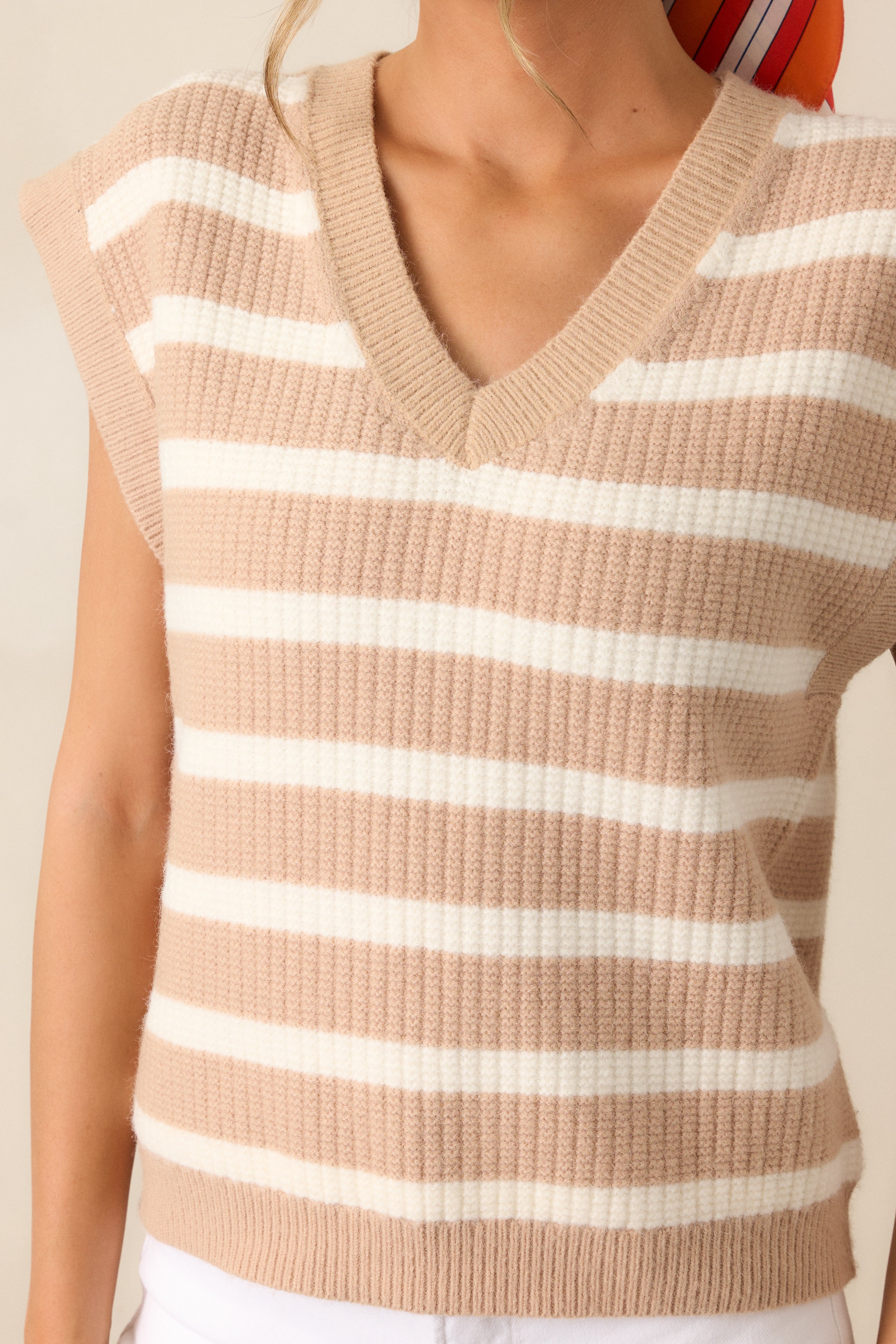 Zoom in on the crisp white stripes running across the tan sweater, highlighting the clean V-neckline and the breezy feel of the cap sleeves.