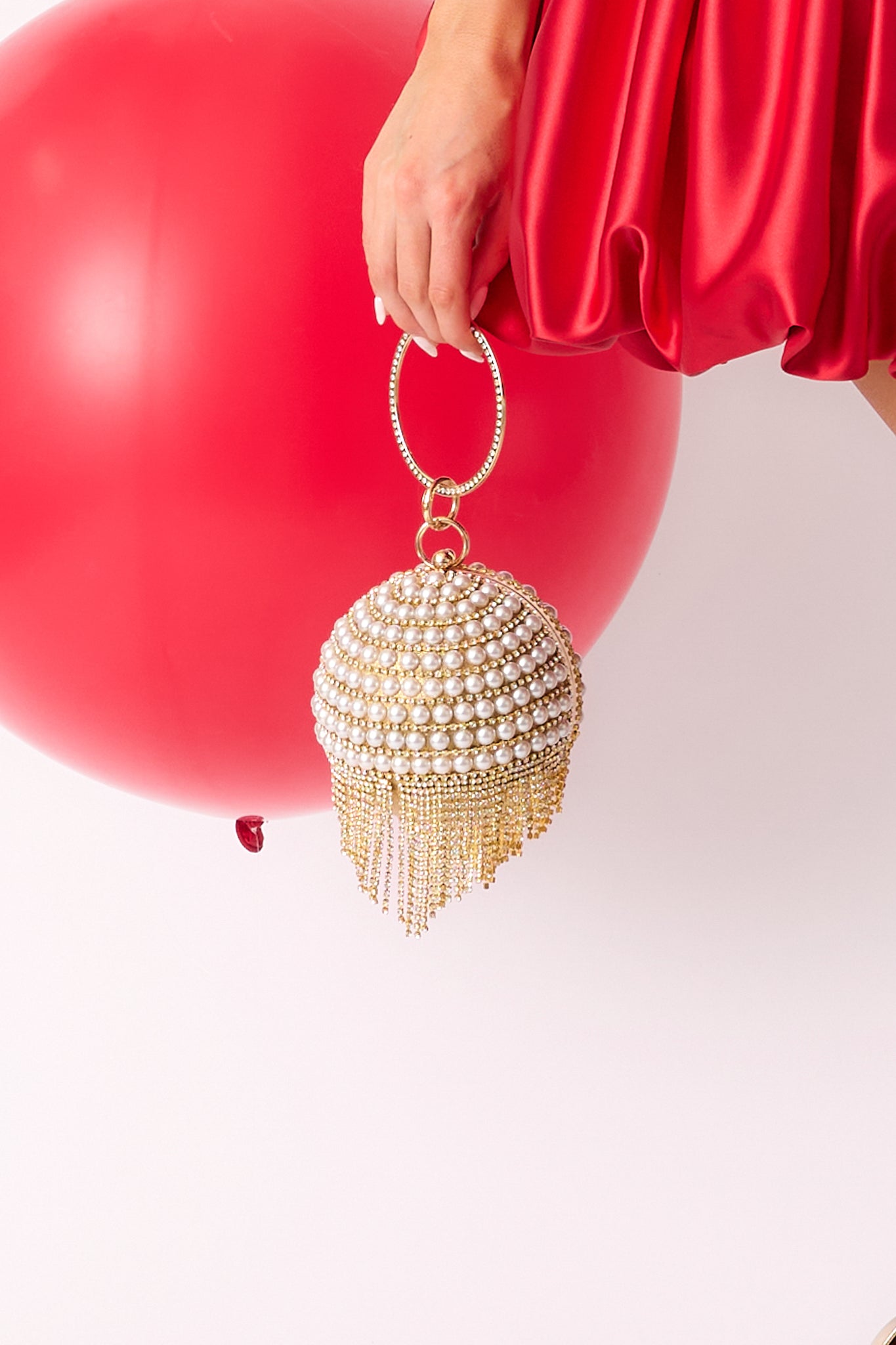 A view of the gold and ivory clutch showcasing its circular body adorned with rows of ivory faux pearls and diamonds, and a gold diamond-embossed handle.