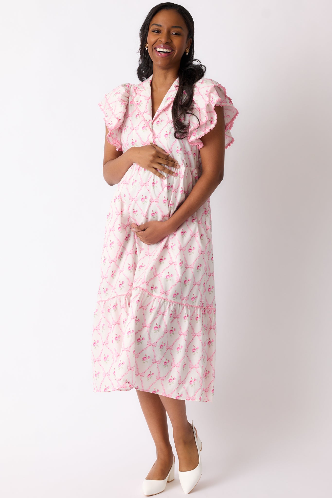 A front angled shot of the dress showcasing the pink trim, bump-friendly design, and floral bow pattern across the midi-length silhouette.