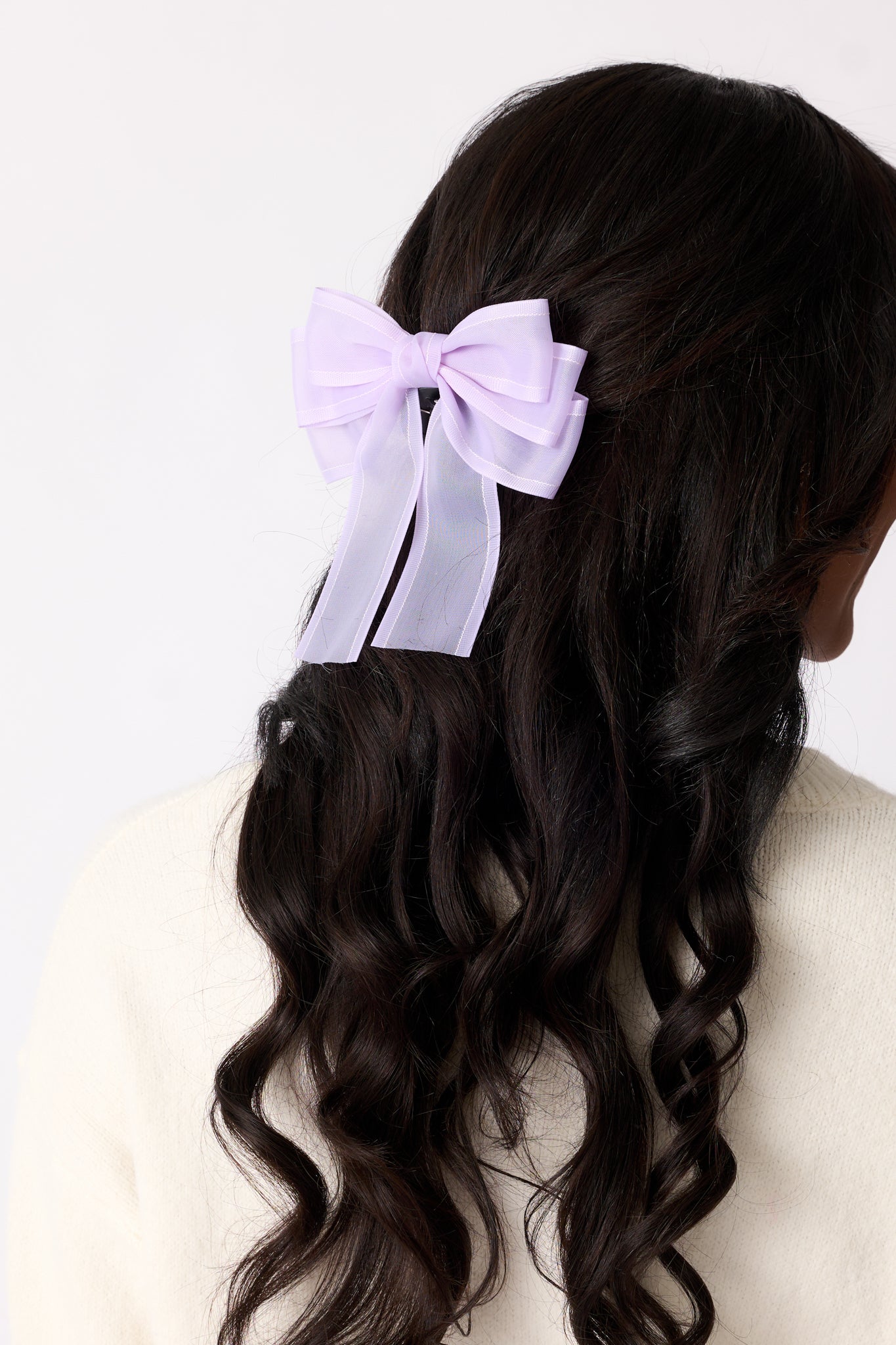 A lavender bow with a layered design displayed prominently, showing its sheer purple material and delicate structure.