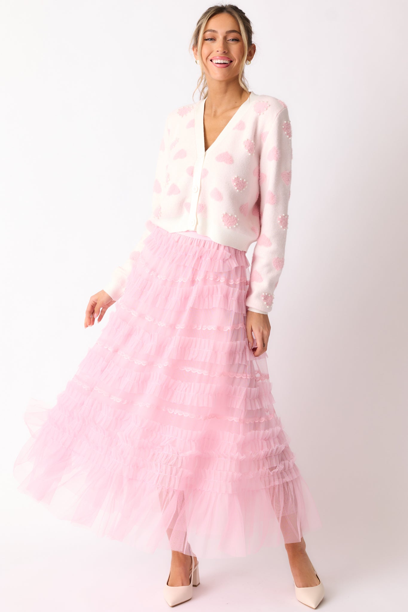 The light pink skirt from the front, showcasing its midi length, elastic waistband, and delicate lace detailing with a ruffle tulle overlay.