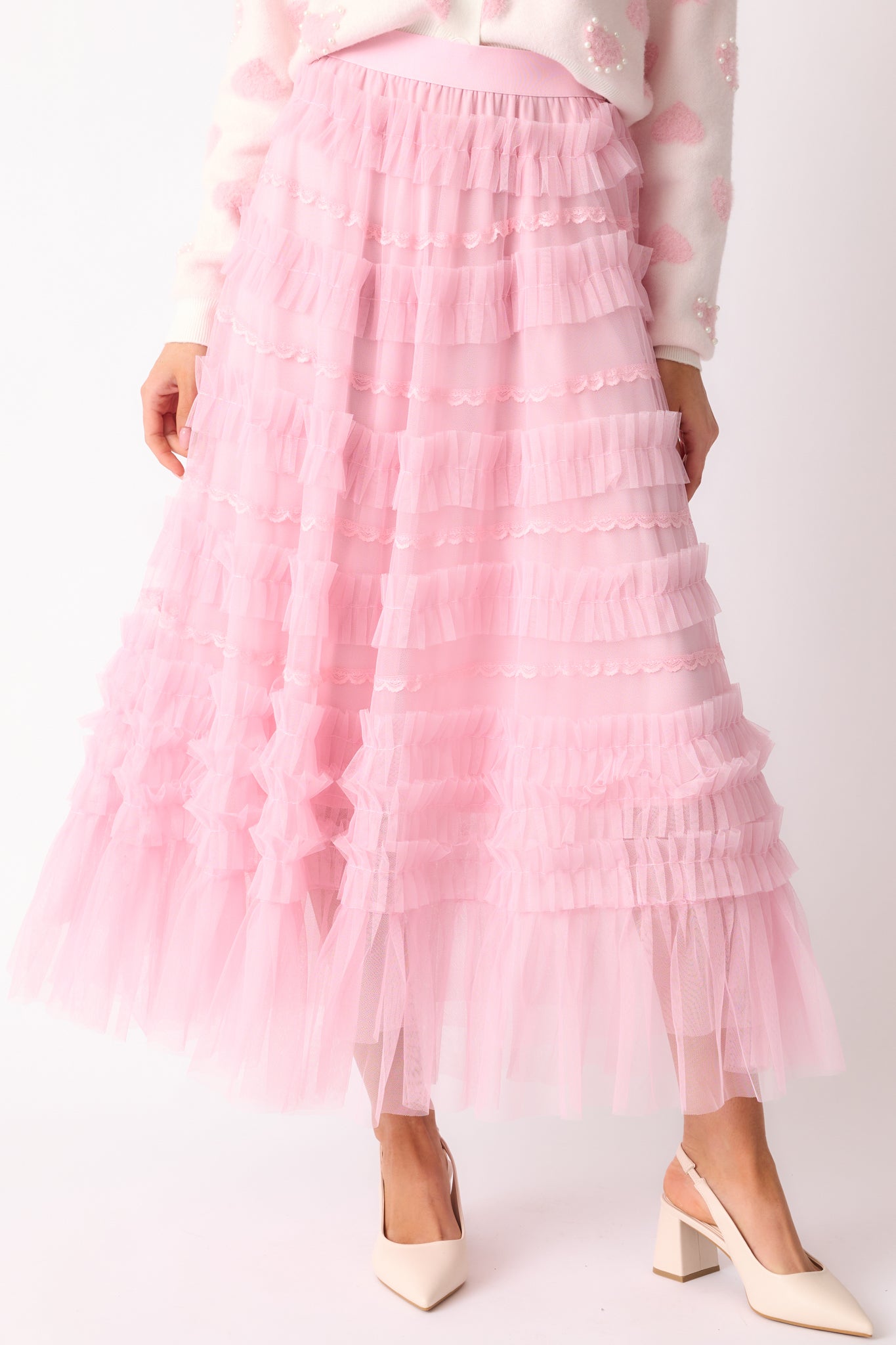 A detailed shot highlighting the delicate lace detailing and the soft ruffle tulle overlay on the light pink skirt.