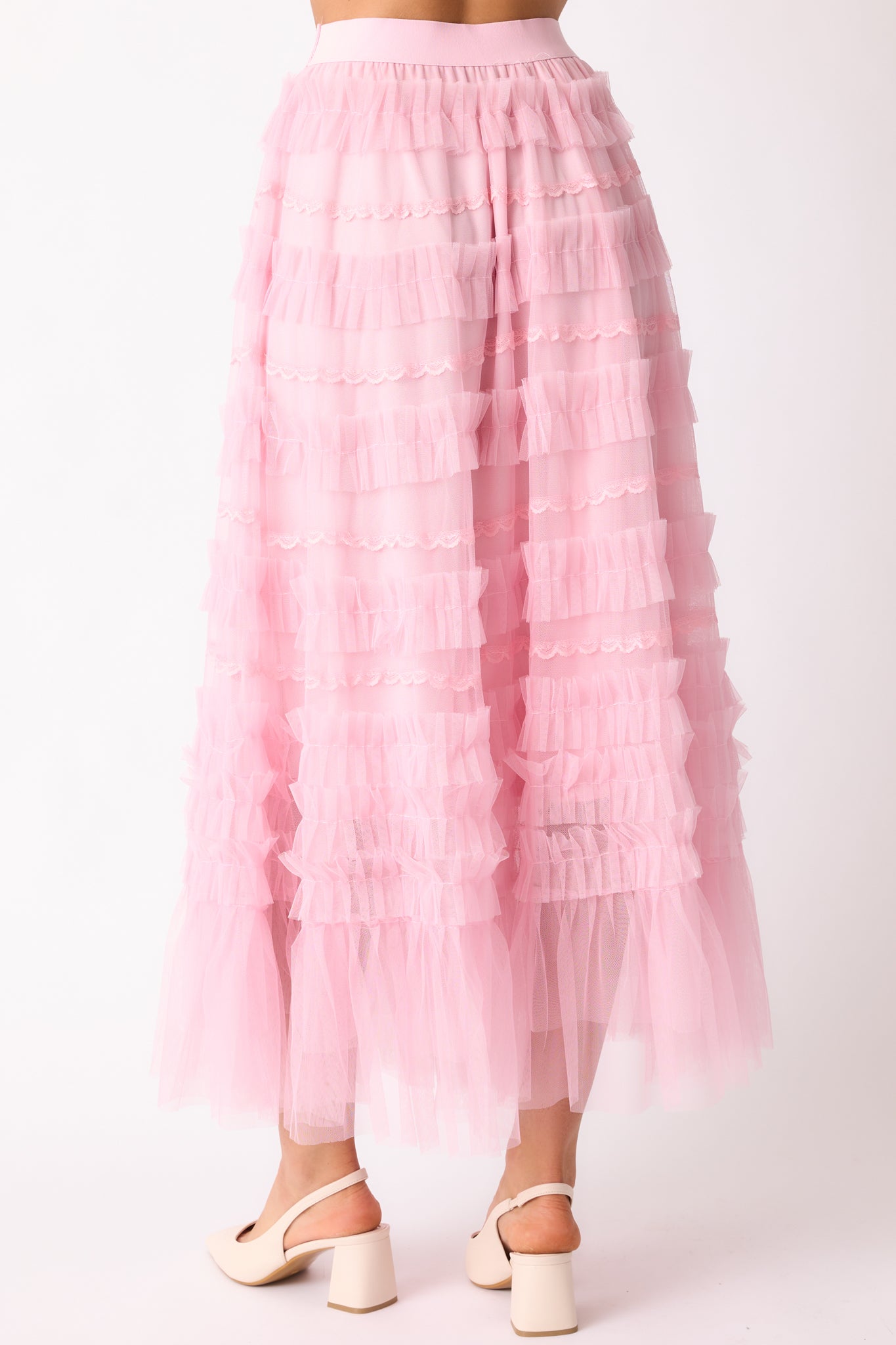 The back of the light pink skirt, showing the elastic waistband and the layered ruffle tulle overlay with lace detailing at the hem.