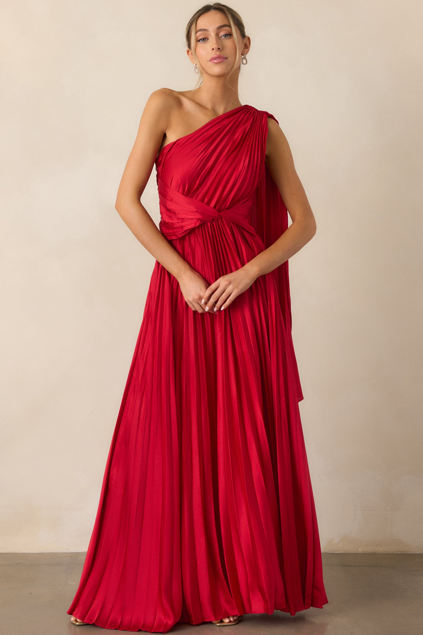 A dynamic shot of the red dress highlighting the one-shoulder neckline, twist waist, and pleated fabric with the shoulder scarf trailing elegantly.