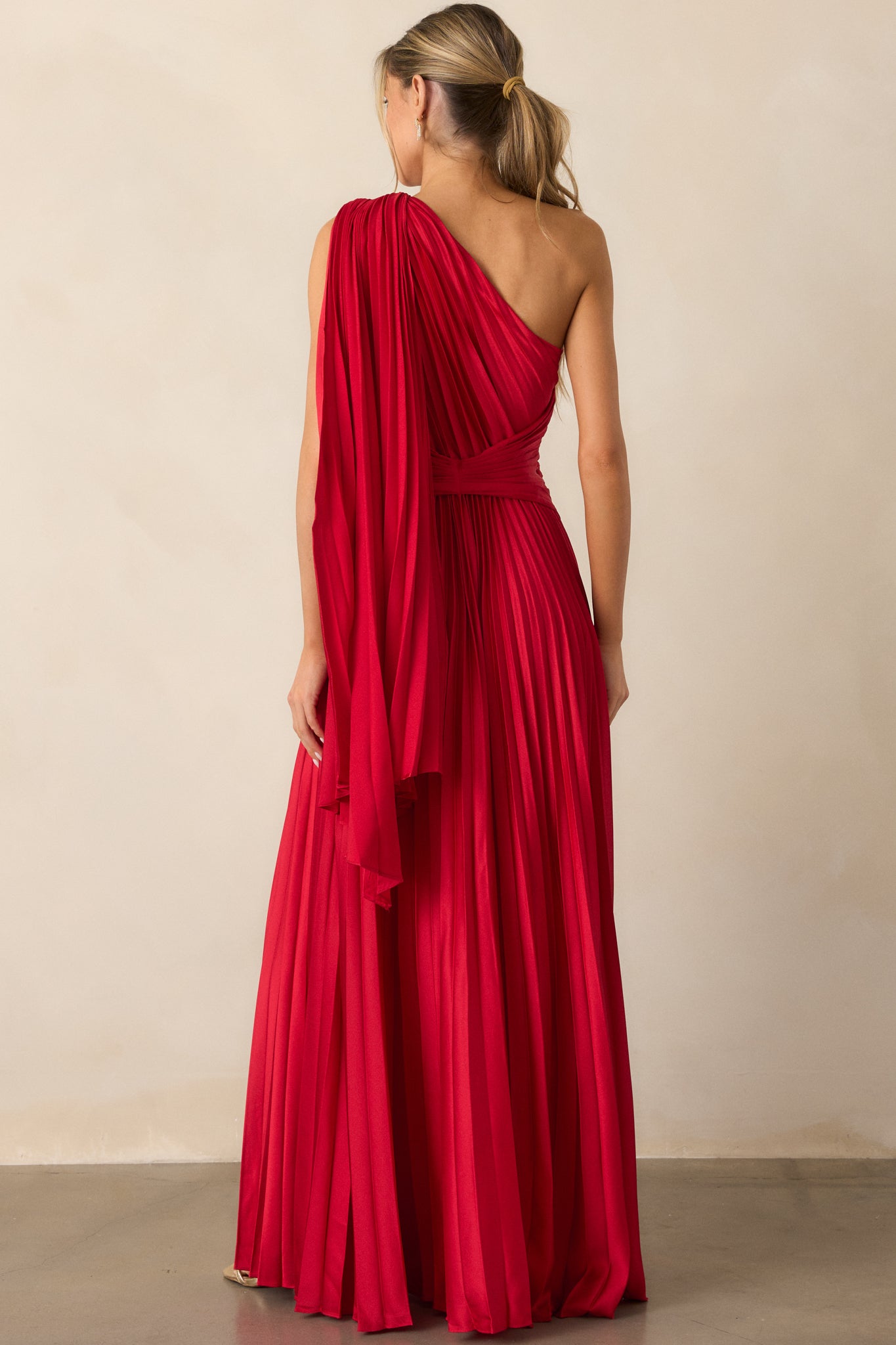 A close-up of the one-shoulder neckline and twist waist detailing, focusing on the texture of the pleated fabric and the shoulder scarf draping.