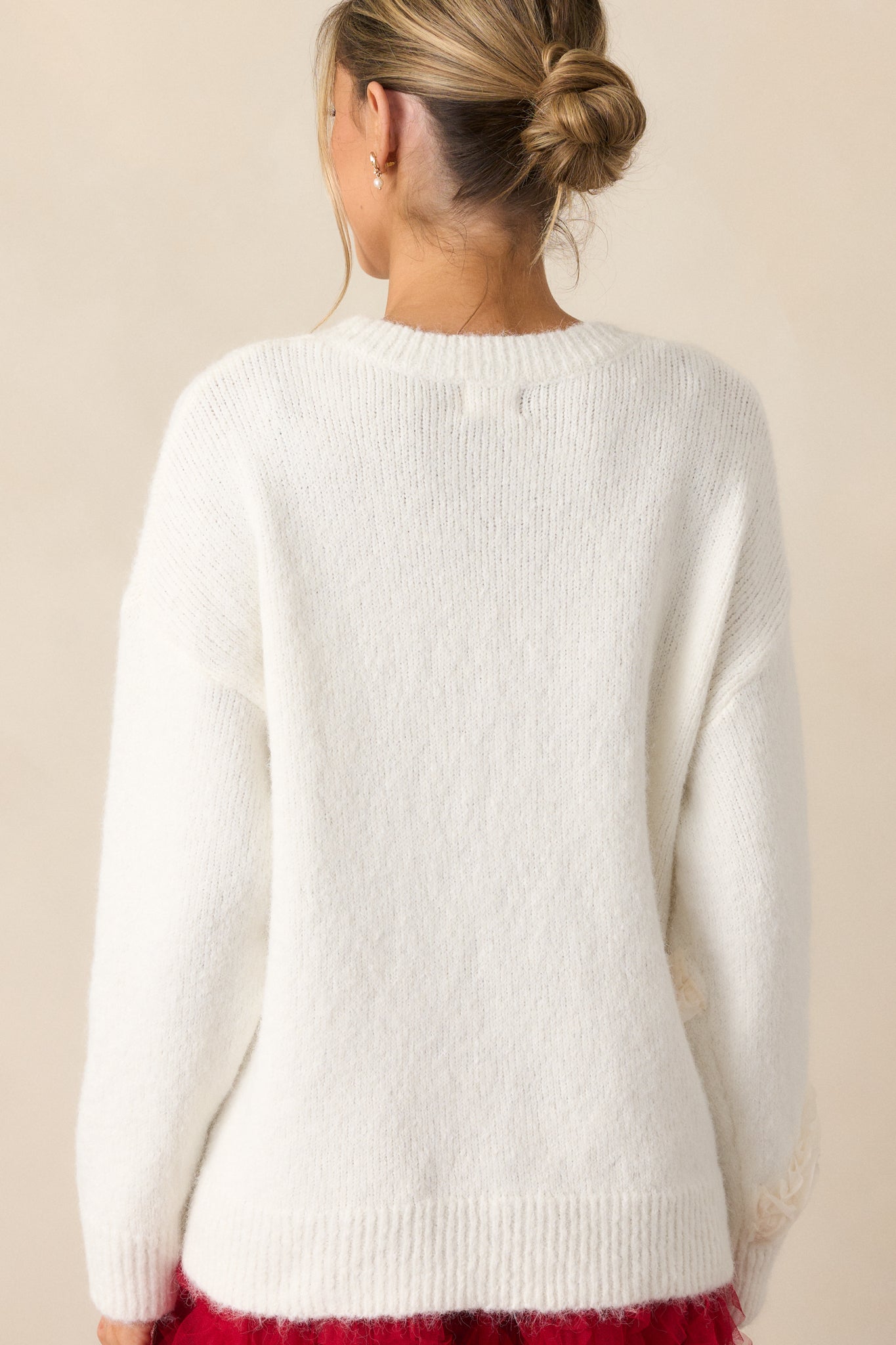 Back view of the ivory sweater, showcasing the plain back design, long sleeves, and rib-knit hems.