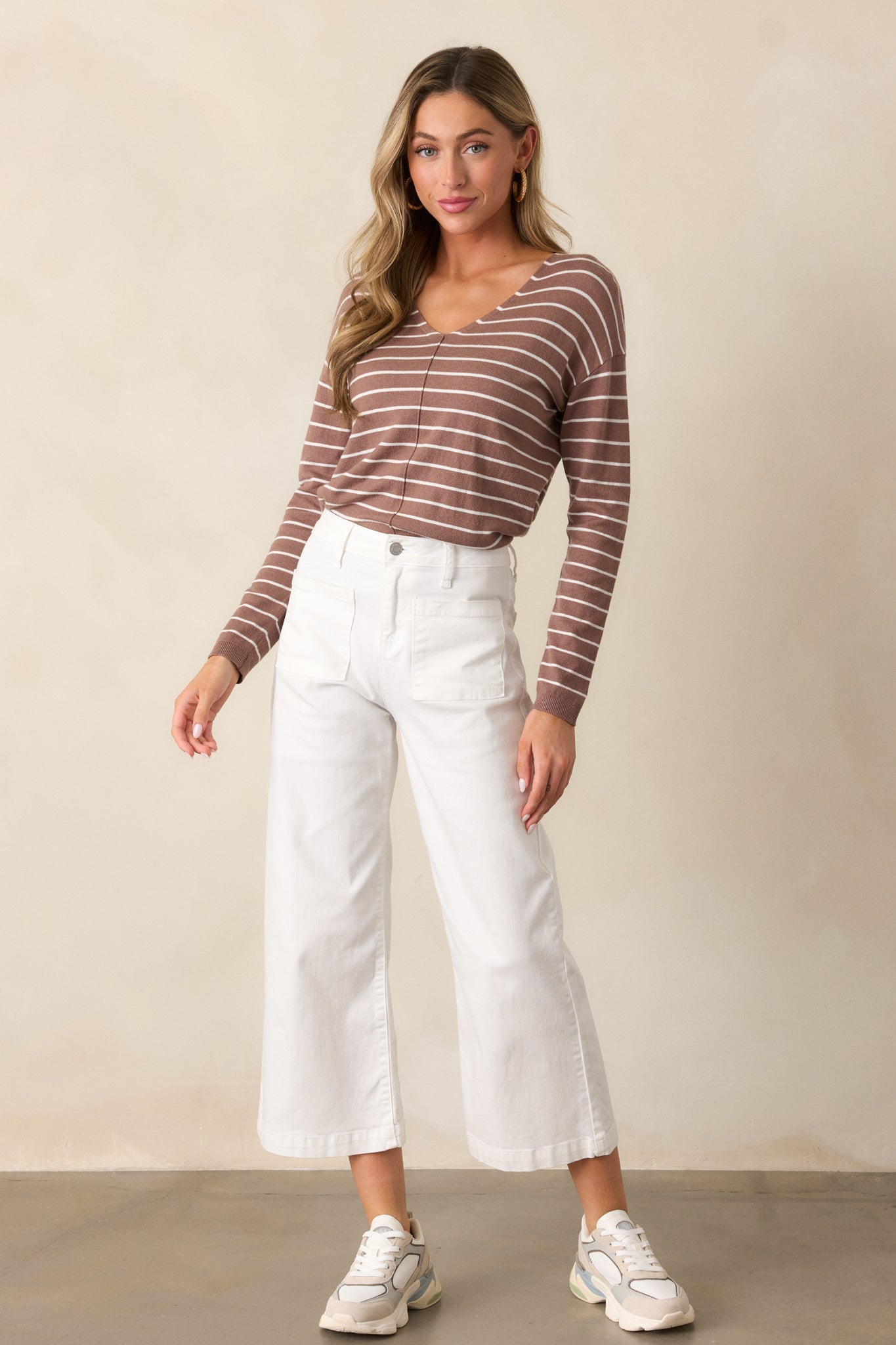 A full-length shot of the light mocha top featuring a v-neckline and long sleeves. The thin white stripes add a subtle, textured pattern across the relaxed fit of the shirt, with front seam detailing visible along the center.