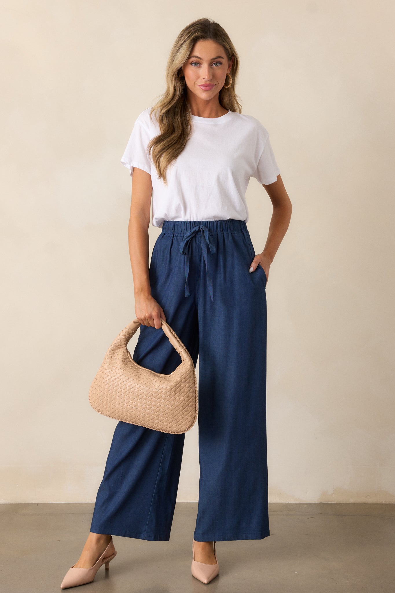 A full-length view of the dark chambray pants, highlighting their high-waisted design, wide legs, and relaxed fit.