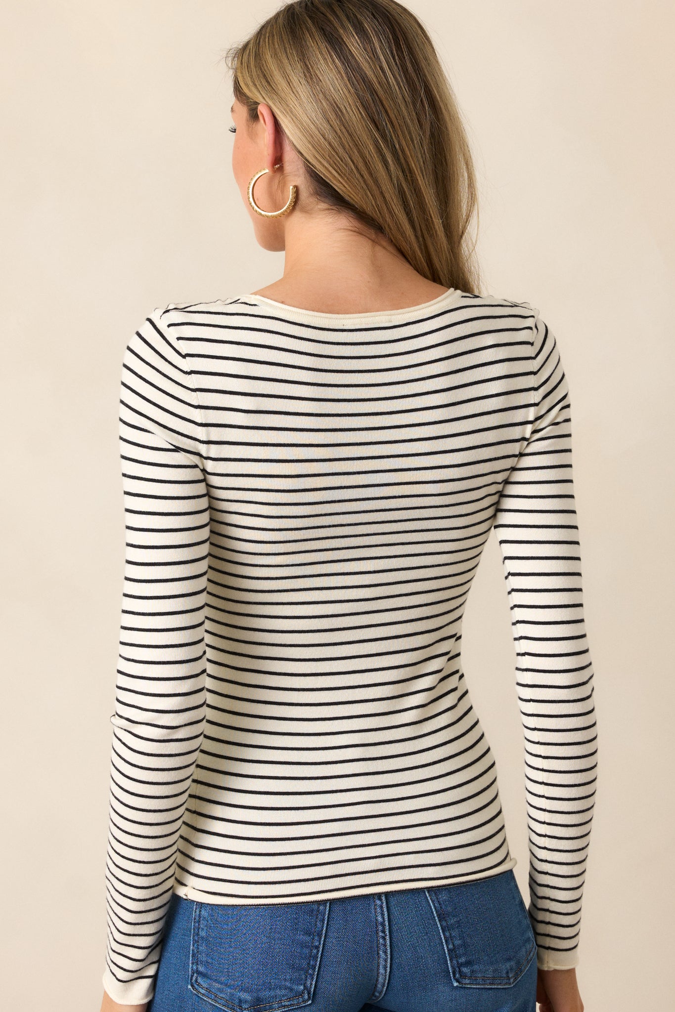 A back view of the ivory top, featuring the same classic black stripe design and long sleeve style.