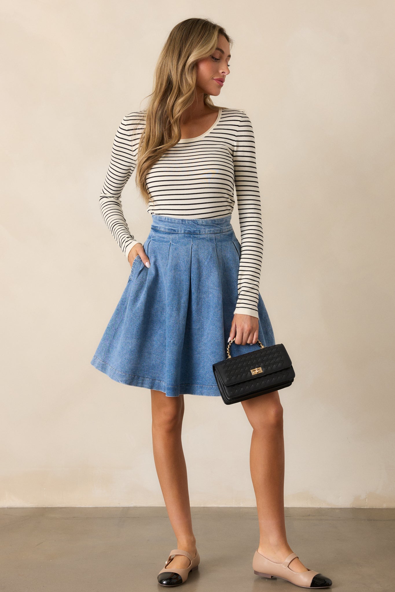 Another full-length view of the high-waisted denim skirt, showcasing its structured fit and pleated details.