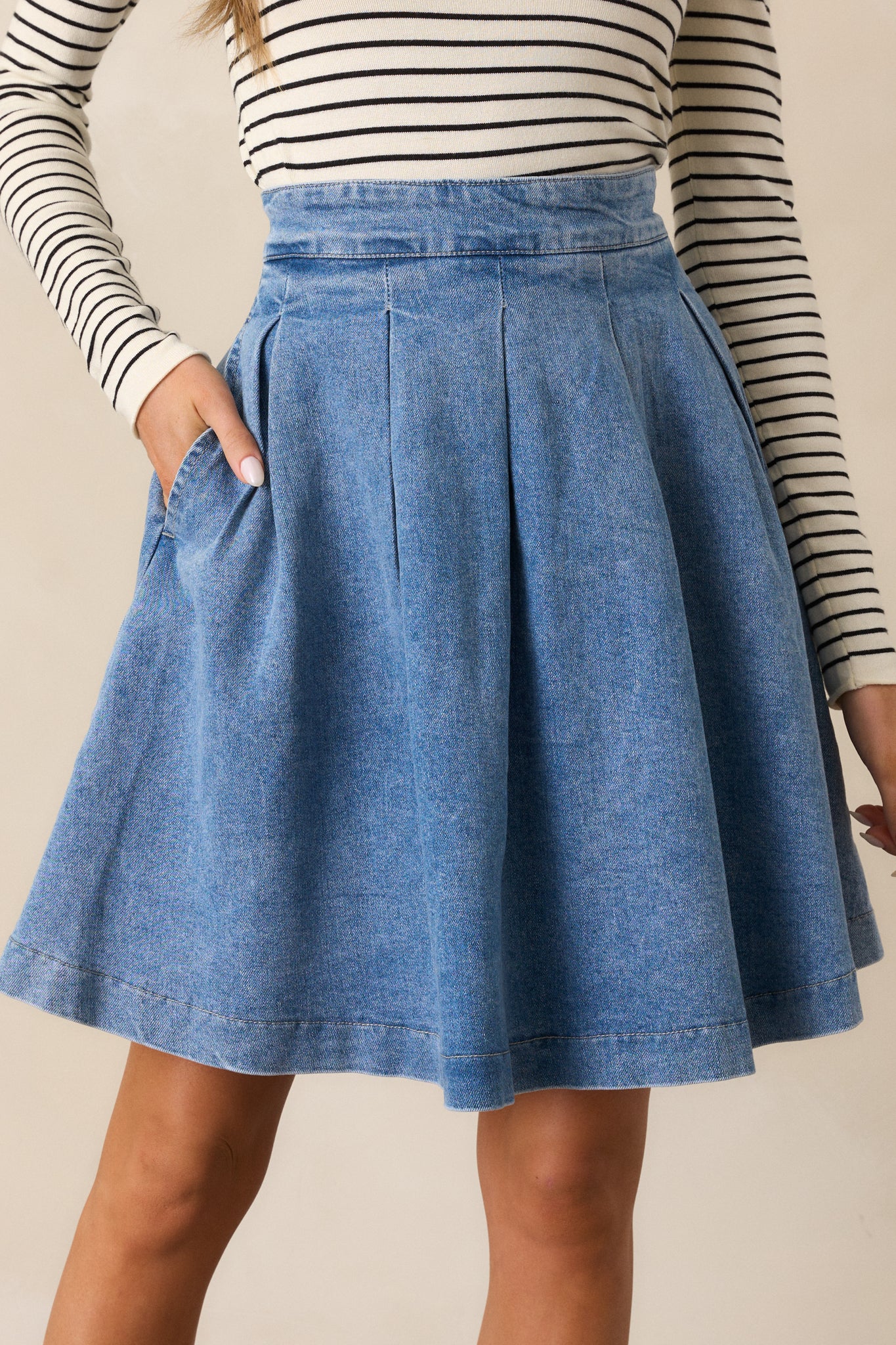 A close-up of the front of the denim skirt, focusing on the high-waisted design and hip pockets.