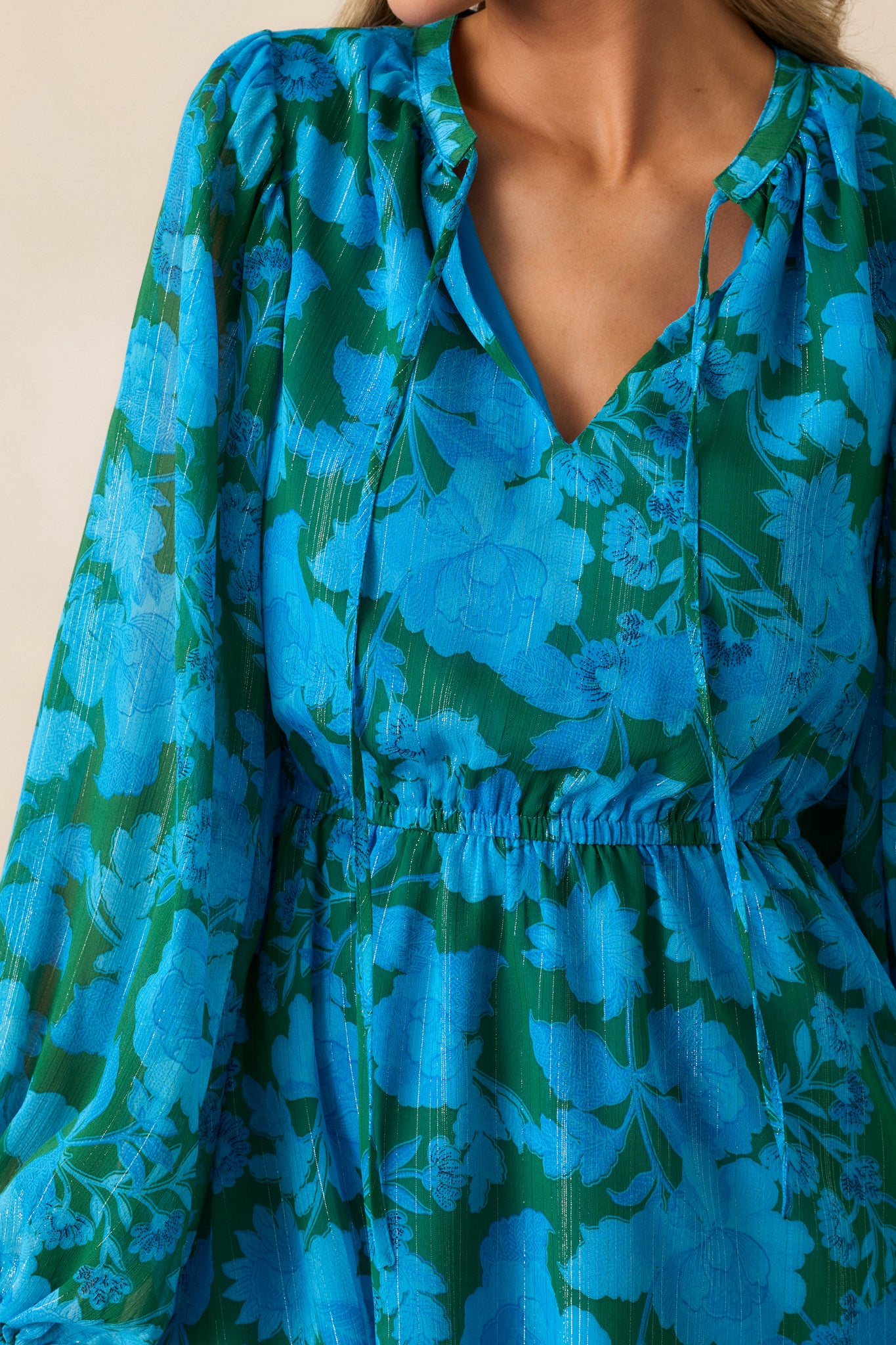 An up-close shot of the beautiful floral design and self-tie collar accent on the blue mini dress.