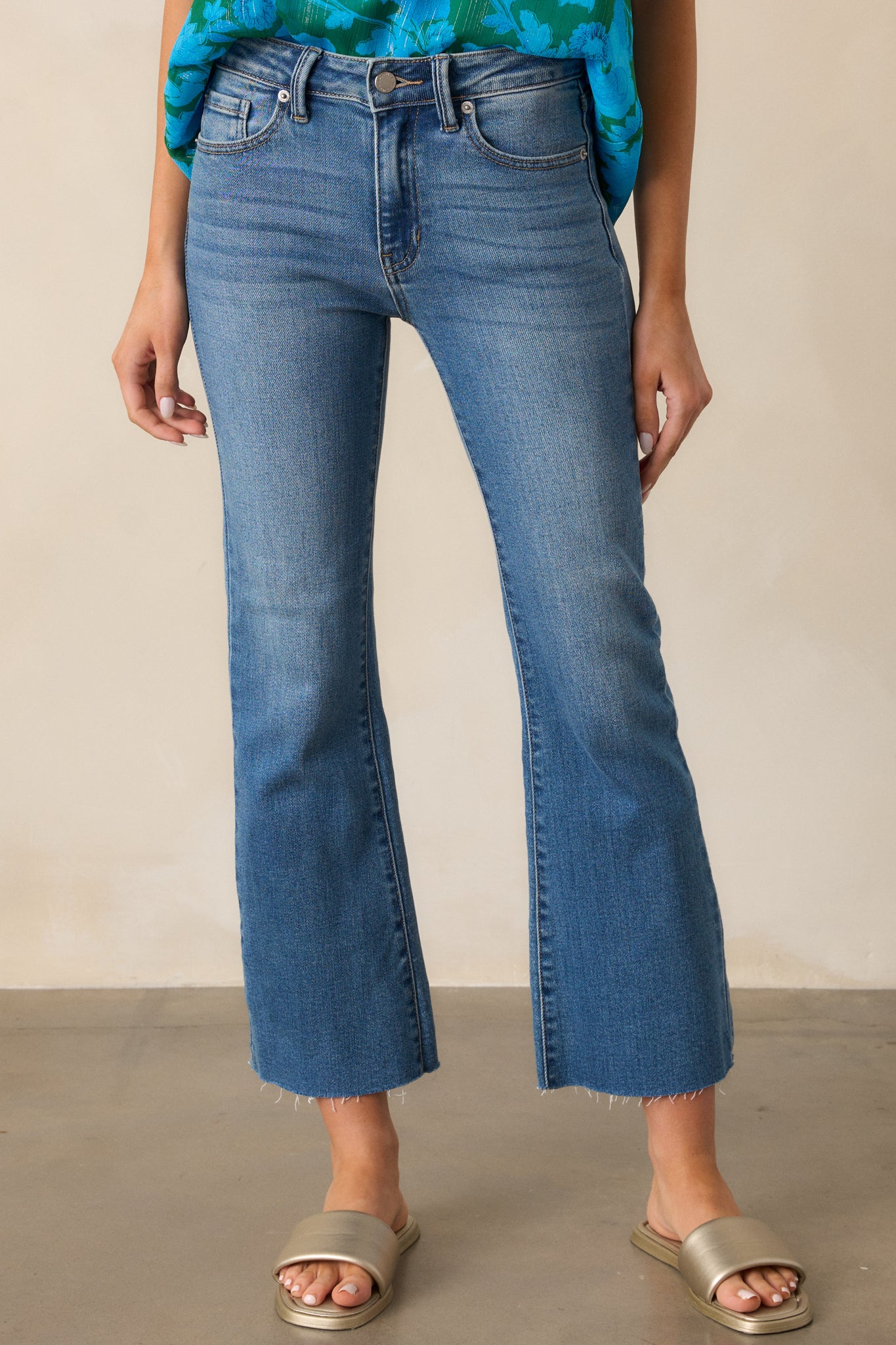 Detailed view of the button zipper closure and hip pockets on the medium wash jeans.