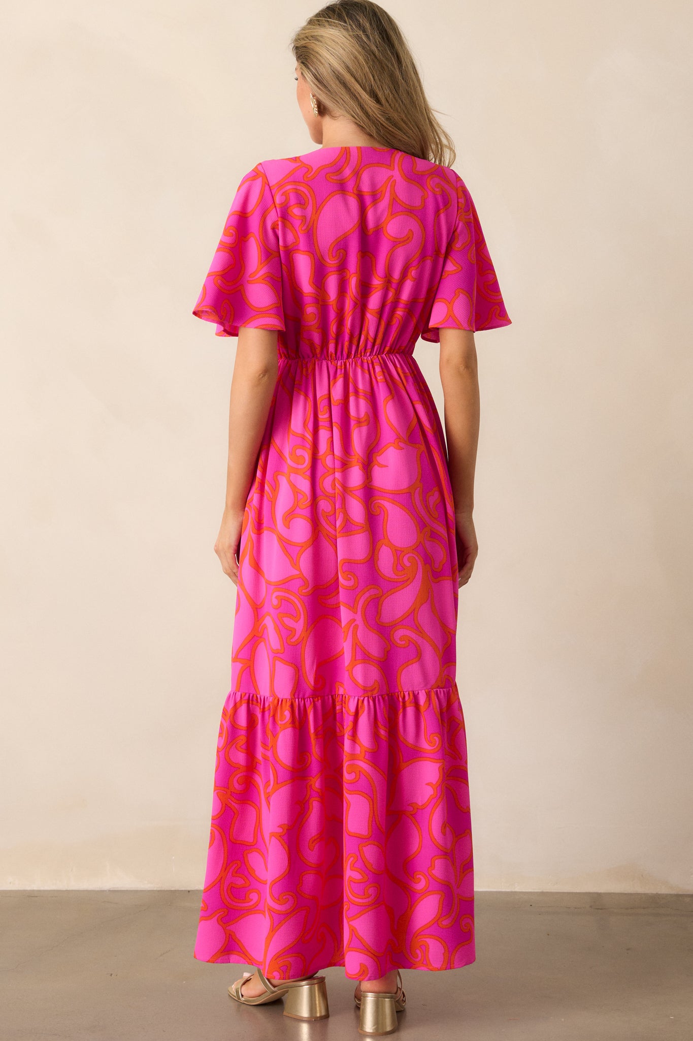 A view of the back of the magenta maxi dress, showing the smooth flow of the fabric and tiered skirt from behind.