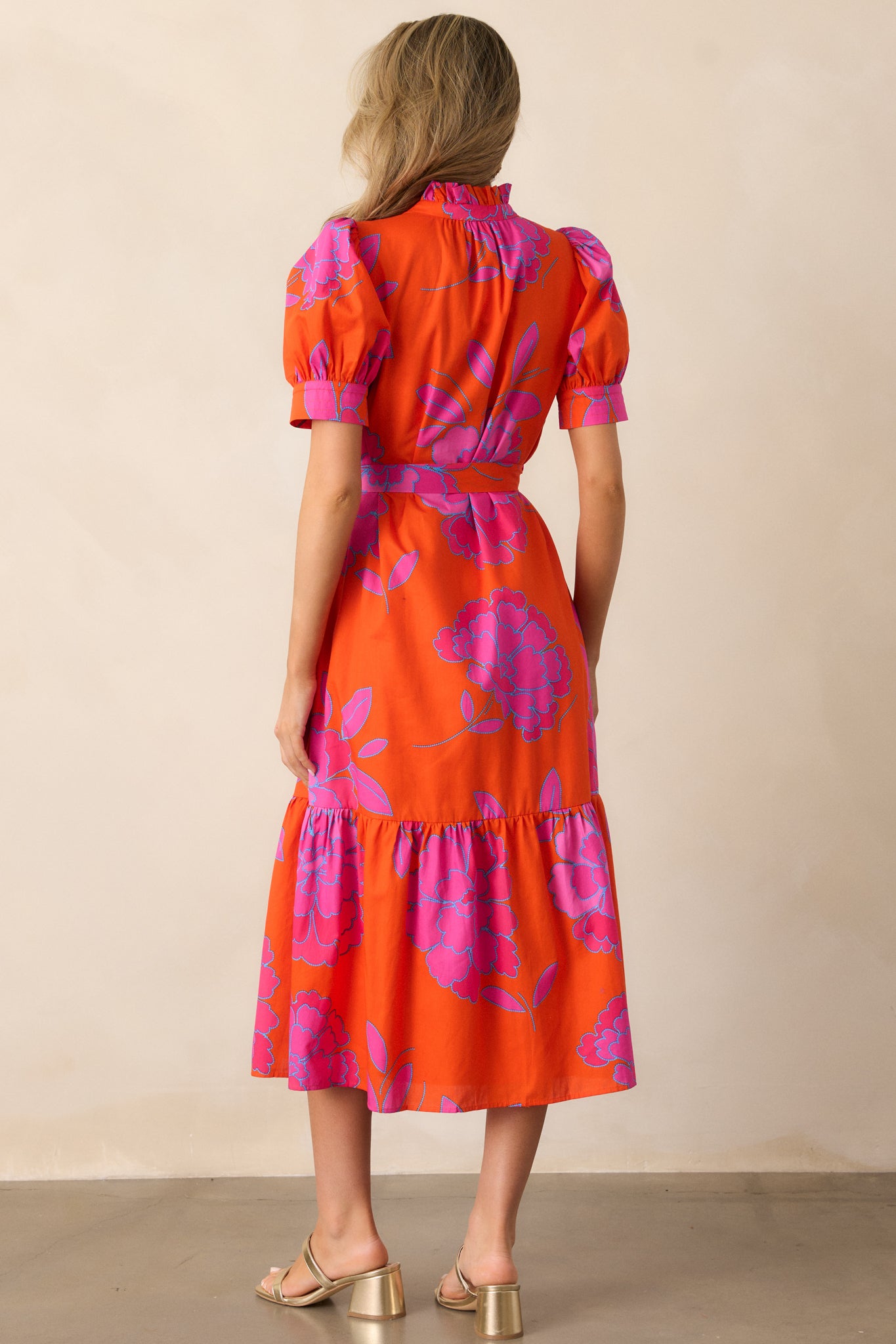 A view of the back of the orange midi dress emphasizing the tiered skirt.