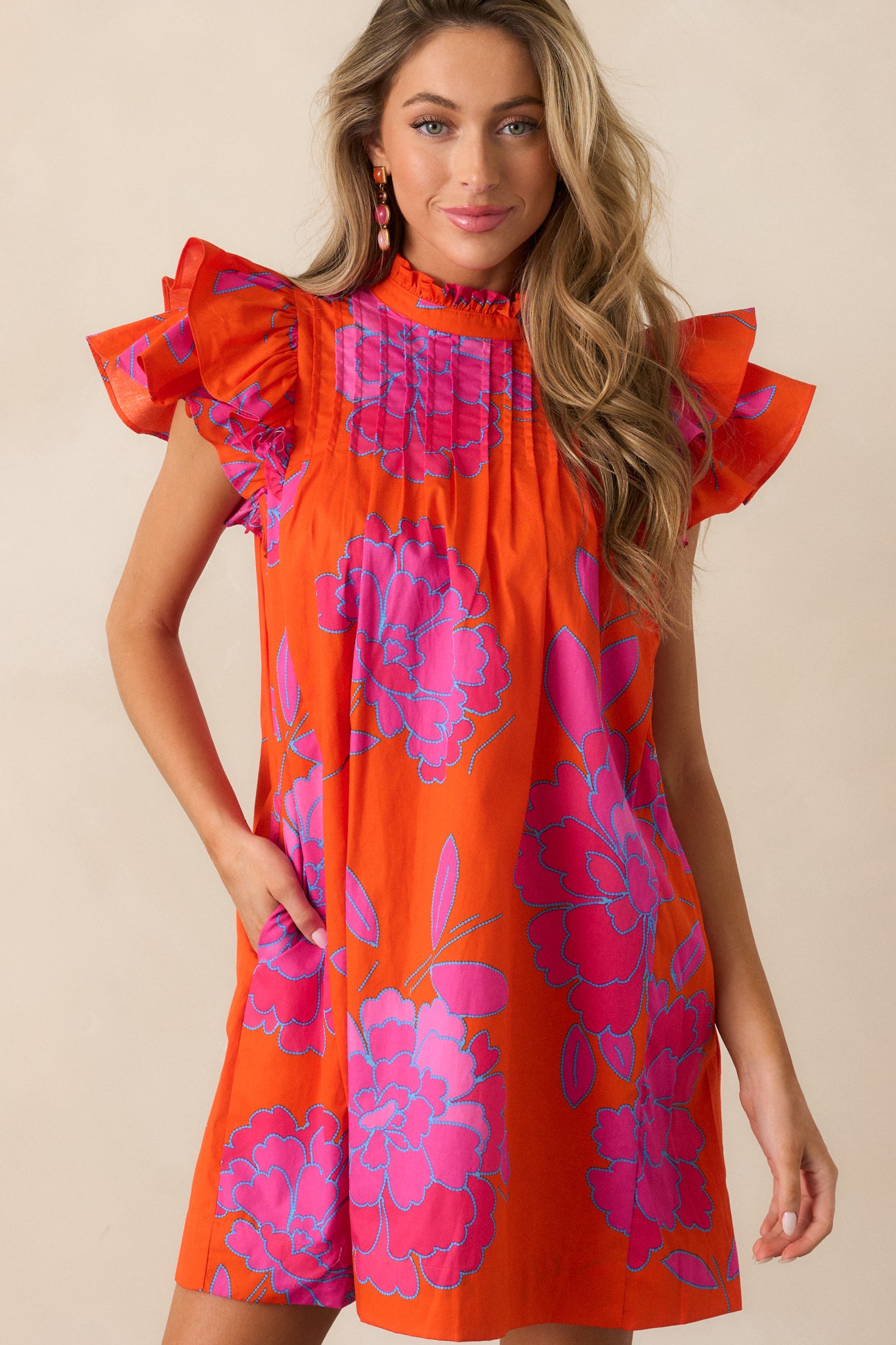 Cropped view of the orange mini dress showcasing the intricate pleated yoke detail and high ruffled neckline.