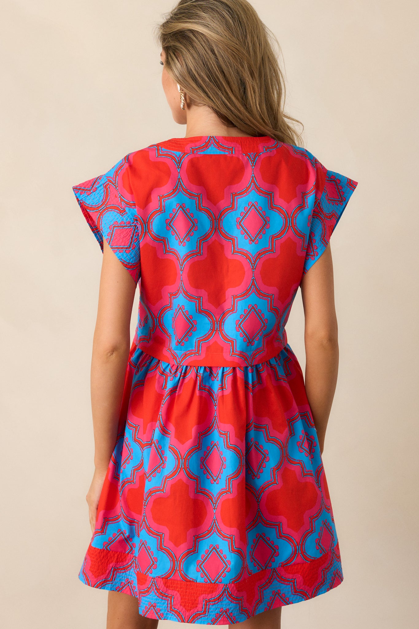 A view of the back of the red mini dress, showcasing the continuation of the pink and blue print and the relaxed fit design.