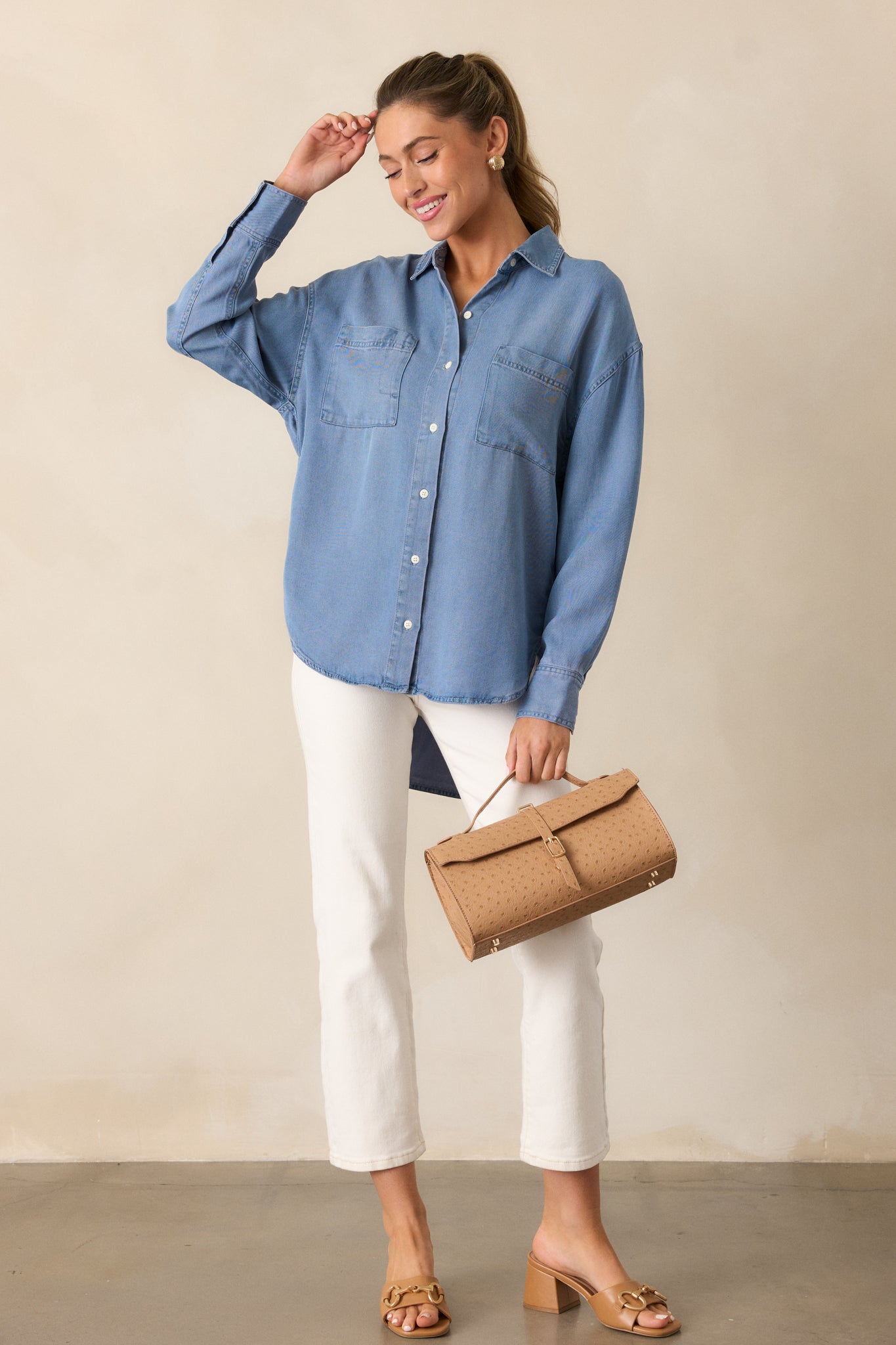 The chambray top in a full-length shot, featuring two chest pockets, a drop cut style, and a button front.