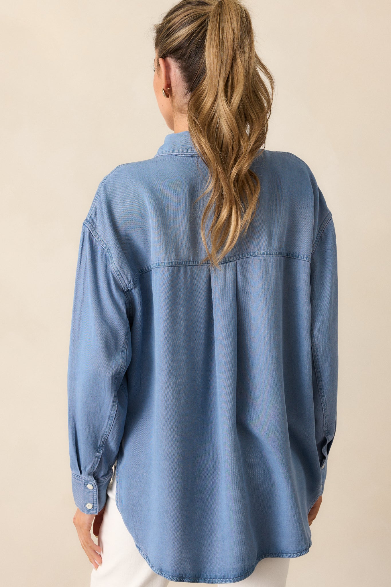 A back view of the chambray top, highlighting the drop cut style and long sleeves.