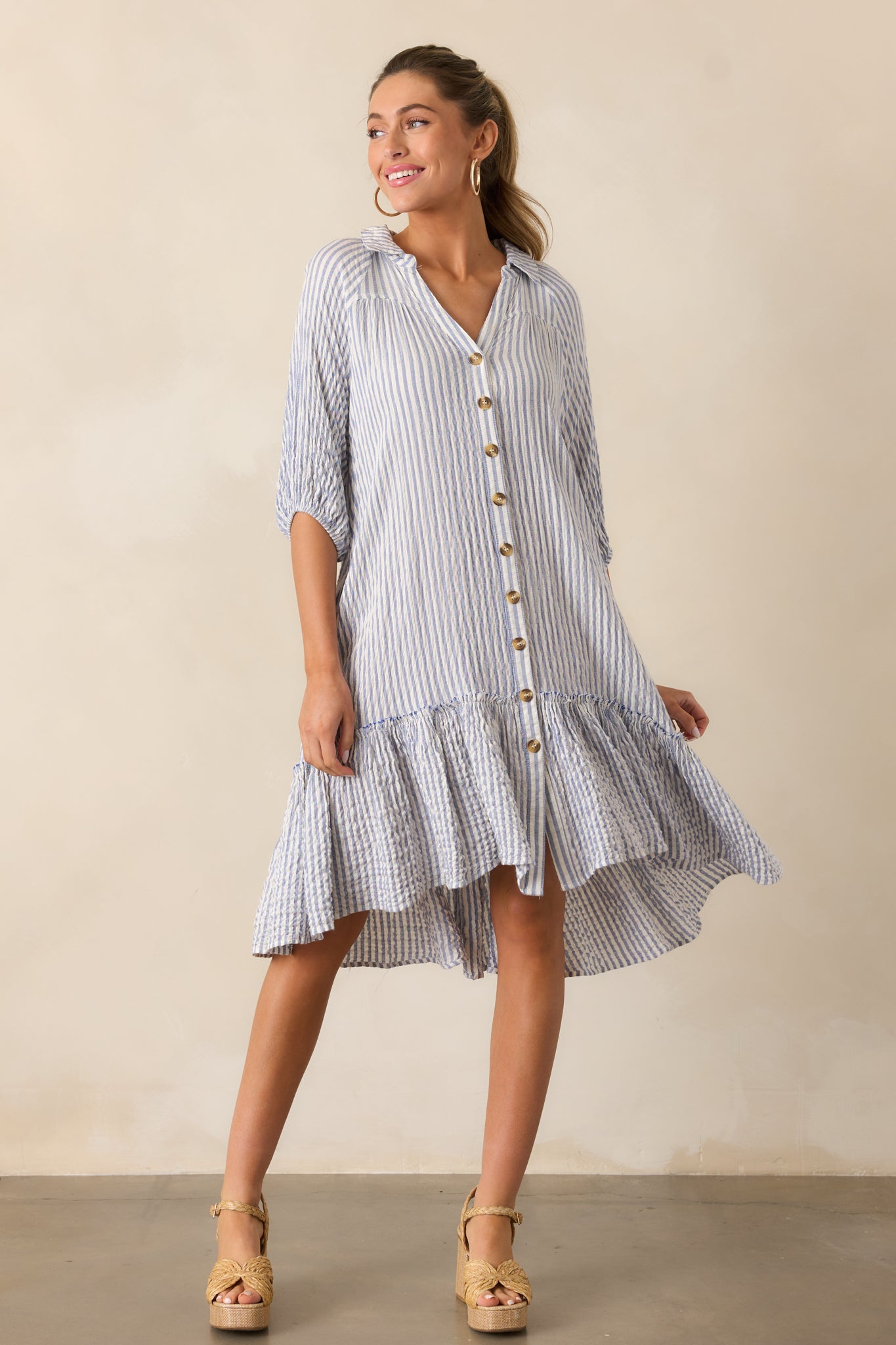 A complete look at the light blue mini dress, emphasizing its drop waist detail, short sleeves, and striped pattern.