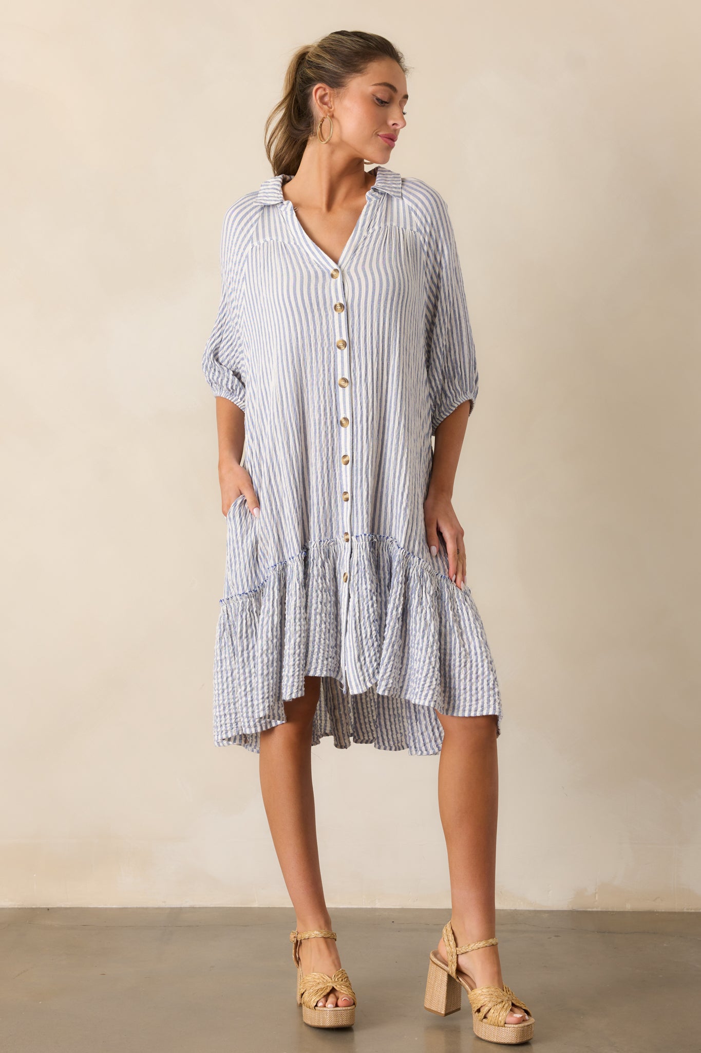 Full-length display of the light blue mini dress with vertical stripes, a collared neckline, and elastic-cuffed sleeves.