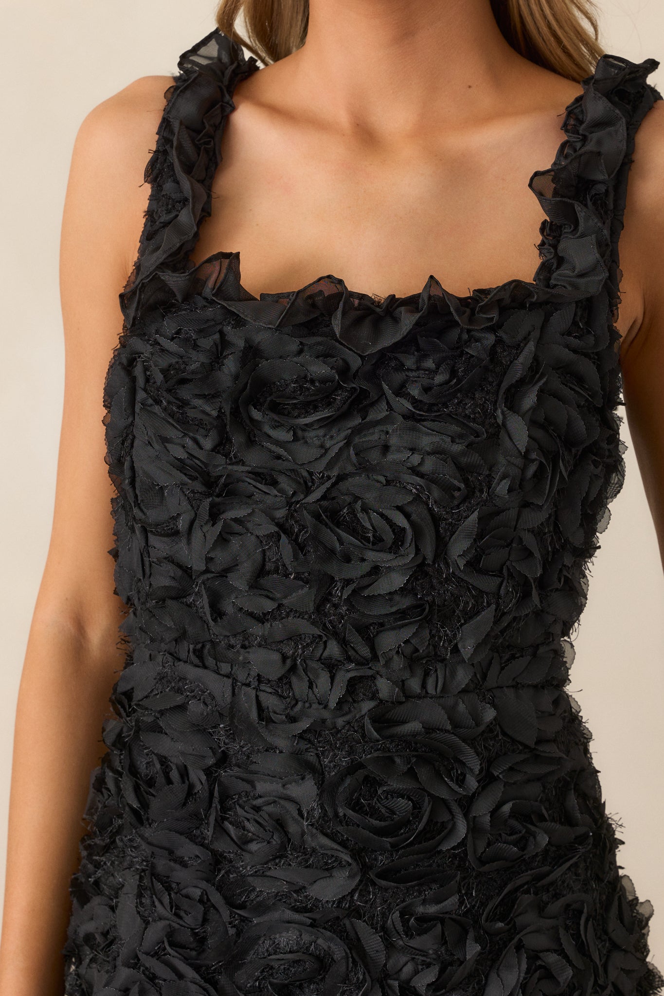 A close-up of the floral applique and ruffle detailing, capturing the texture and intricate craftsmanship on the black fabric.