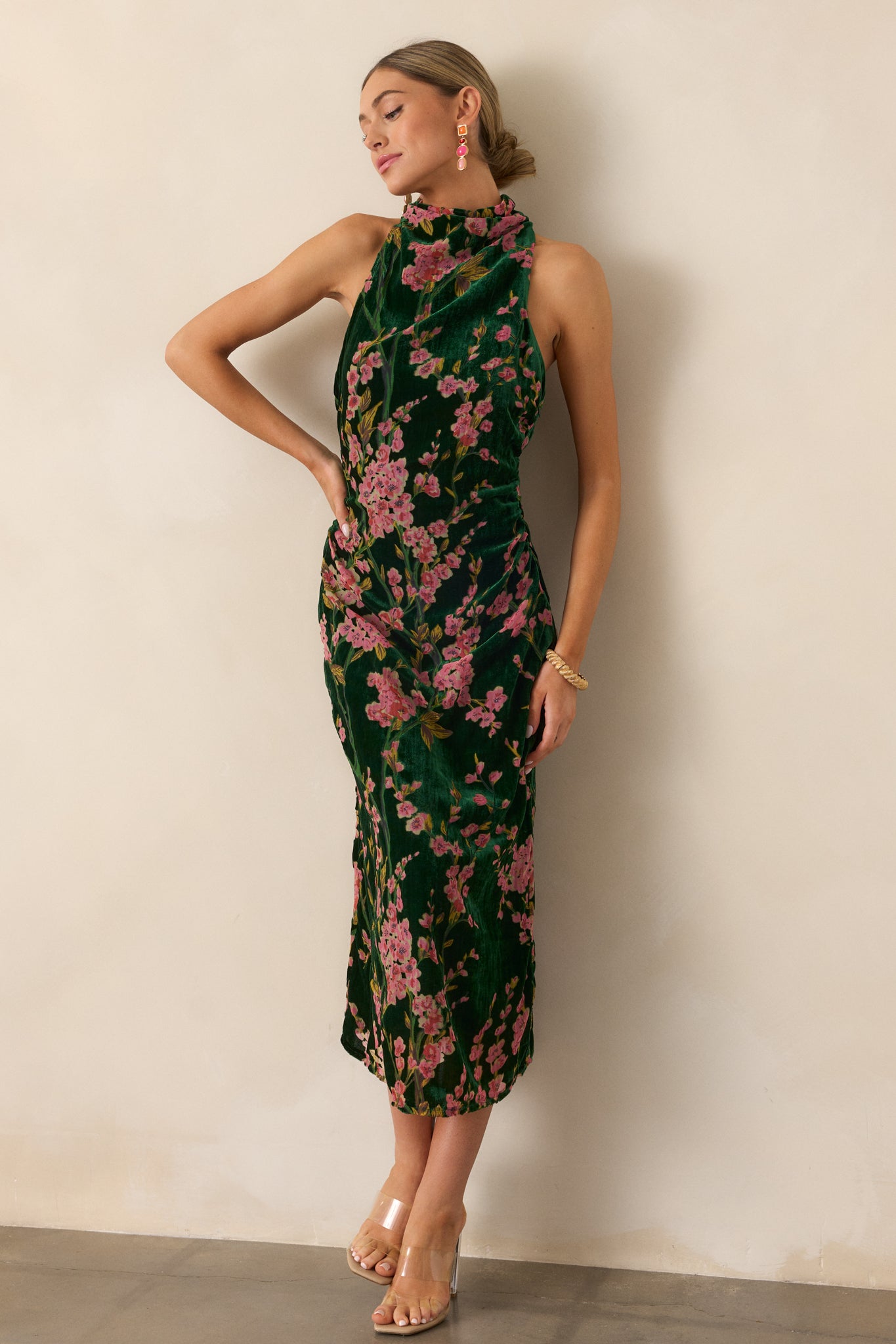 The dress is shown in its entirety, emphasizing the rich velvet fabric and the elegant drape of the halter neckline.