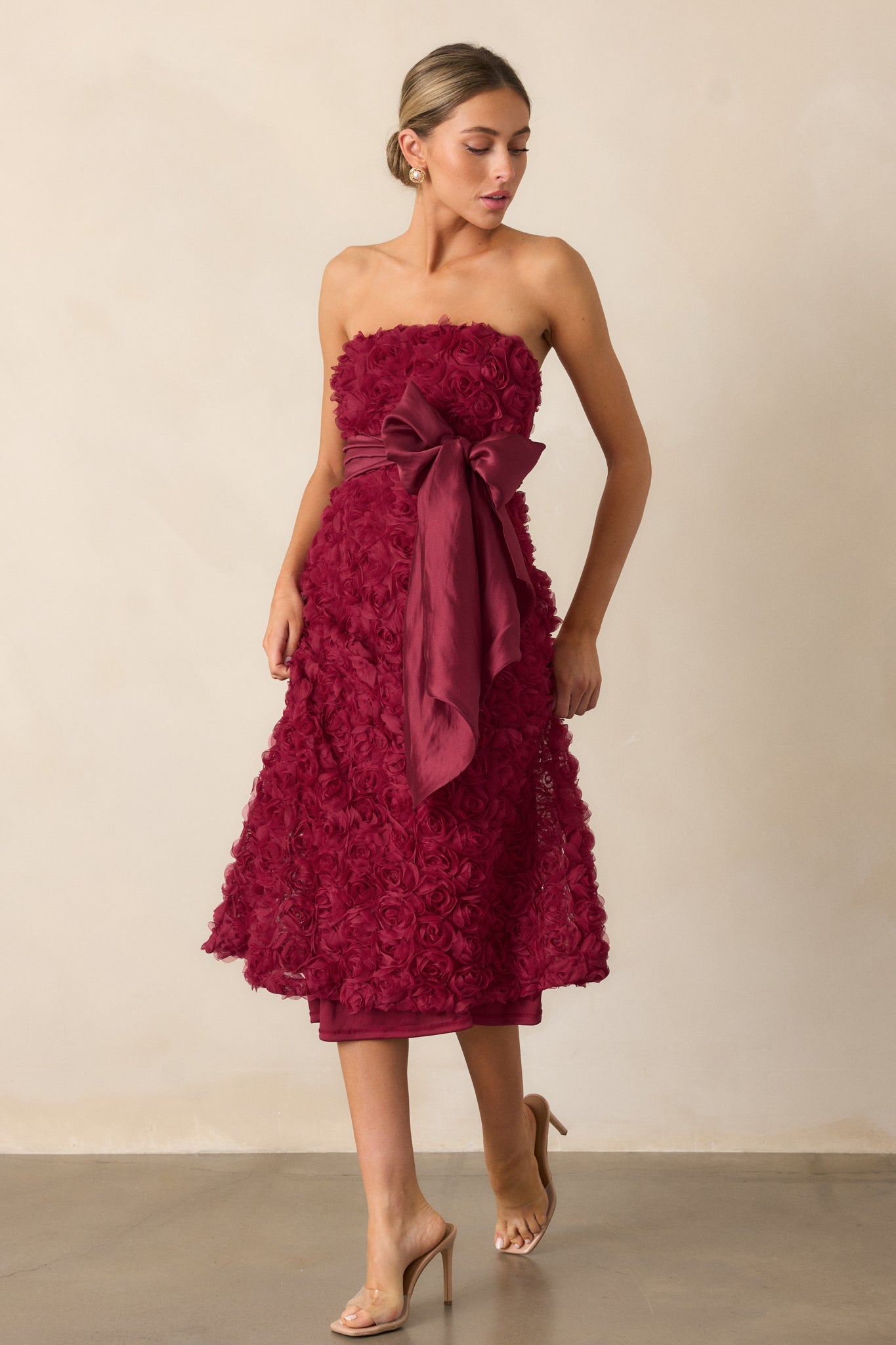 A full-length view of the wine dress, highlighting its strapless neckline and floral applique detailing throughout the fabric.