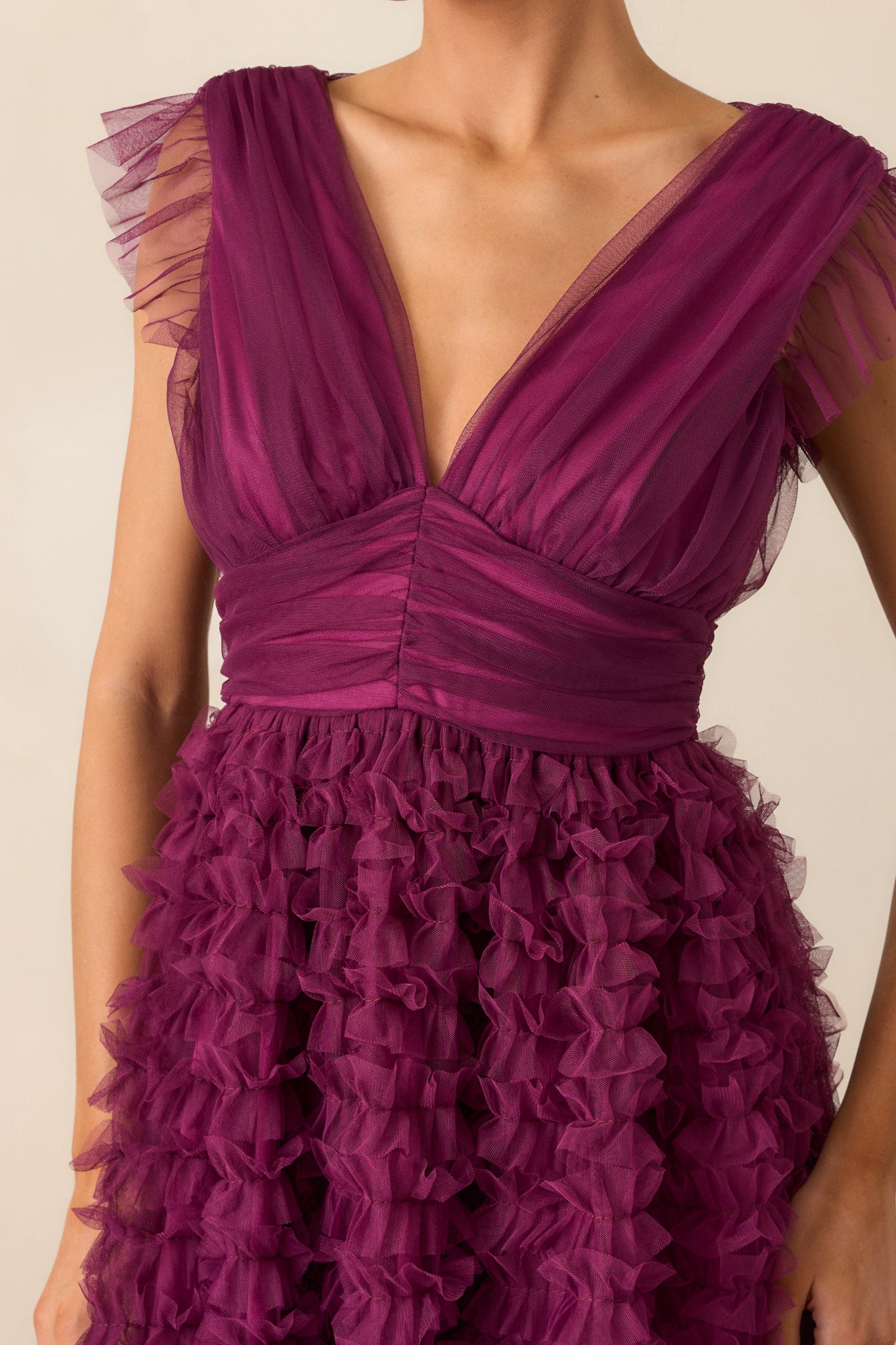 A close-up of the ruffle sleeve detail, highlighting the soft texture and stitching of the plum fabric.