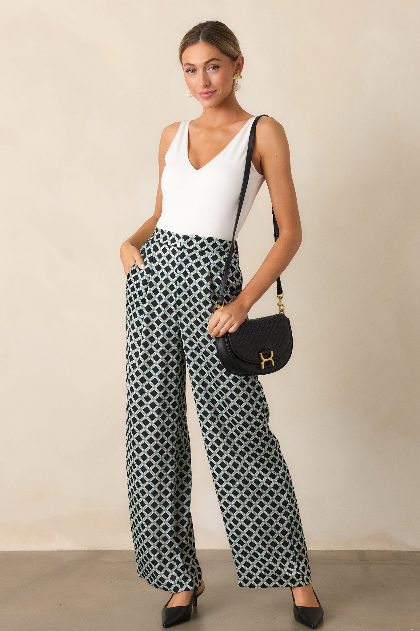 Front-facing full-body image highlighting the bold green and white geometric print and the wide leg silhouette of the black pants.