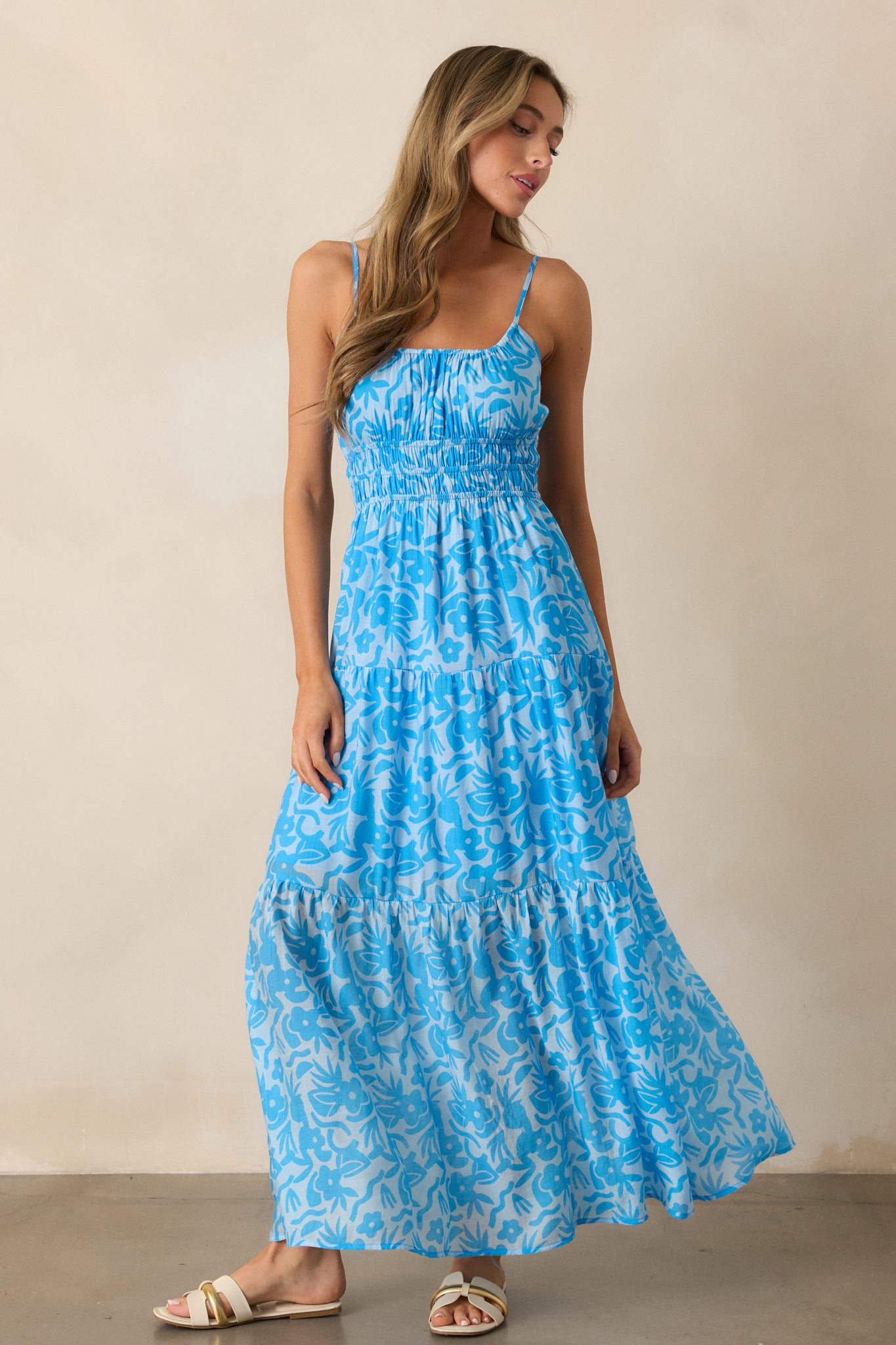  Full-length image of the blue maxi dress, highlighting the elastic waistband and the beautiful floral pattern that flows down the tiered skirt.