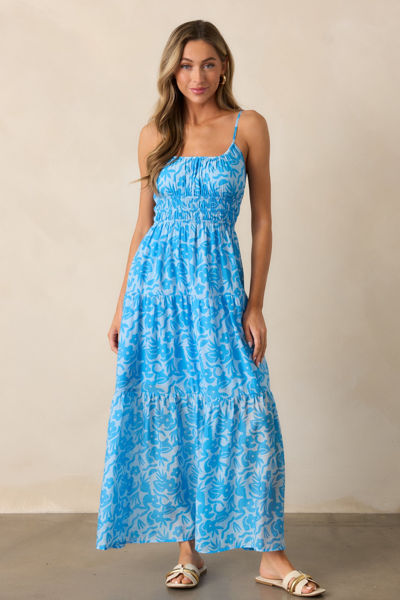  Full view of the blue maxi dress, showcasing the scoop neckline and adjustable spaghetti straps, with a focus on the elegant tiered skirt and floral print.