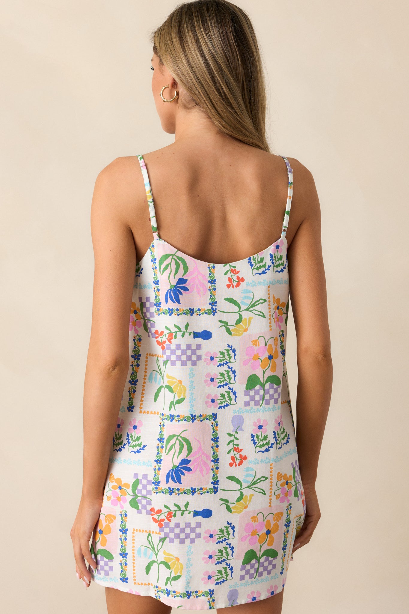 A back view of the ivory mini dress, showing the adjustable straps and continuation of the picnic print.