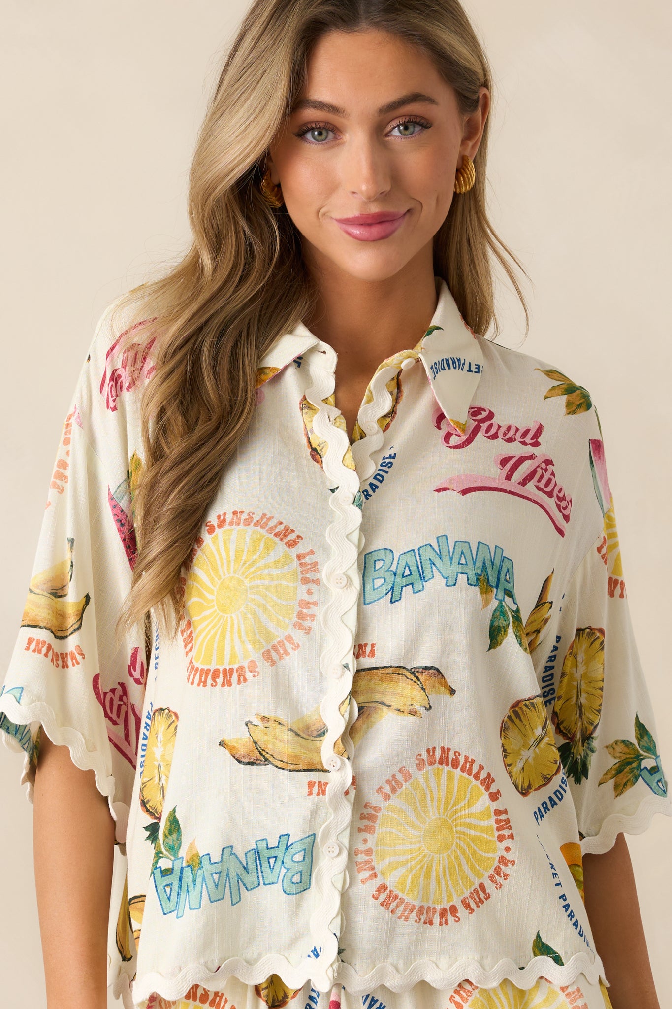 A closer view of the collared neckline and colorful tropical fruit print on the ivory top.