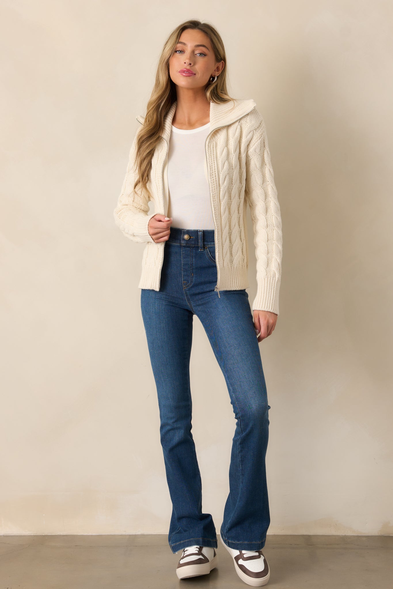 An ivory seasalt cardigan with an oversized collar, cable knit design, and silver zipper front, offering a cozy and stylish look